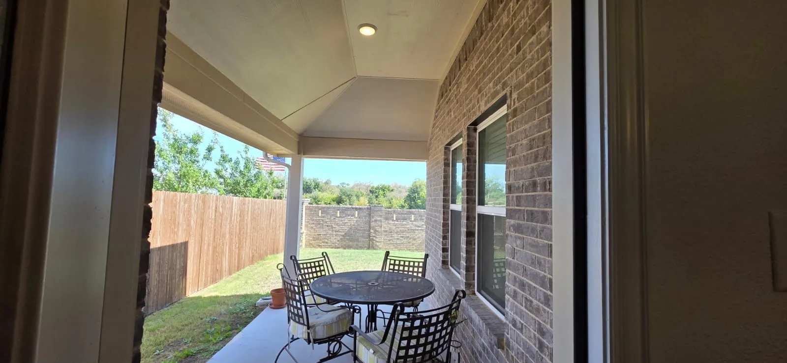 Covered patio with recessed lighting, brick exterior, and a fenced backyard