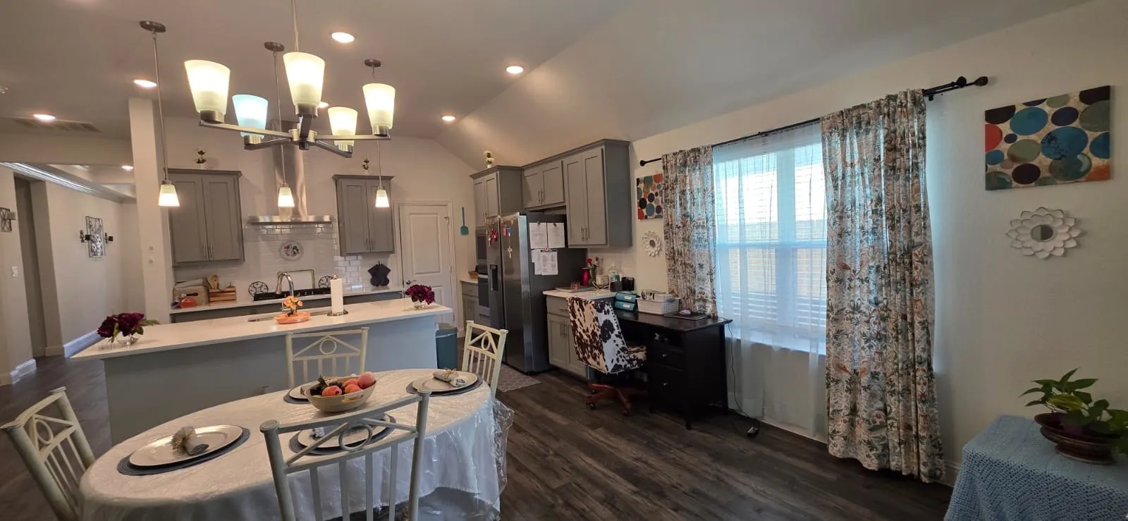 Vaulted ceiling with recessed lighting, wood-finish flooring, white subway tile backsplash, stainless steel appliances, and a central island with countertop seating