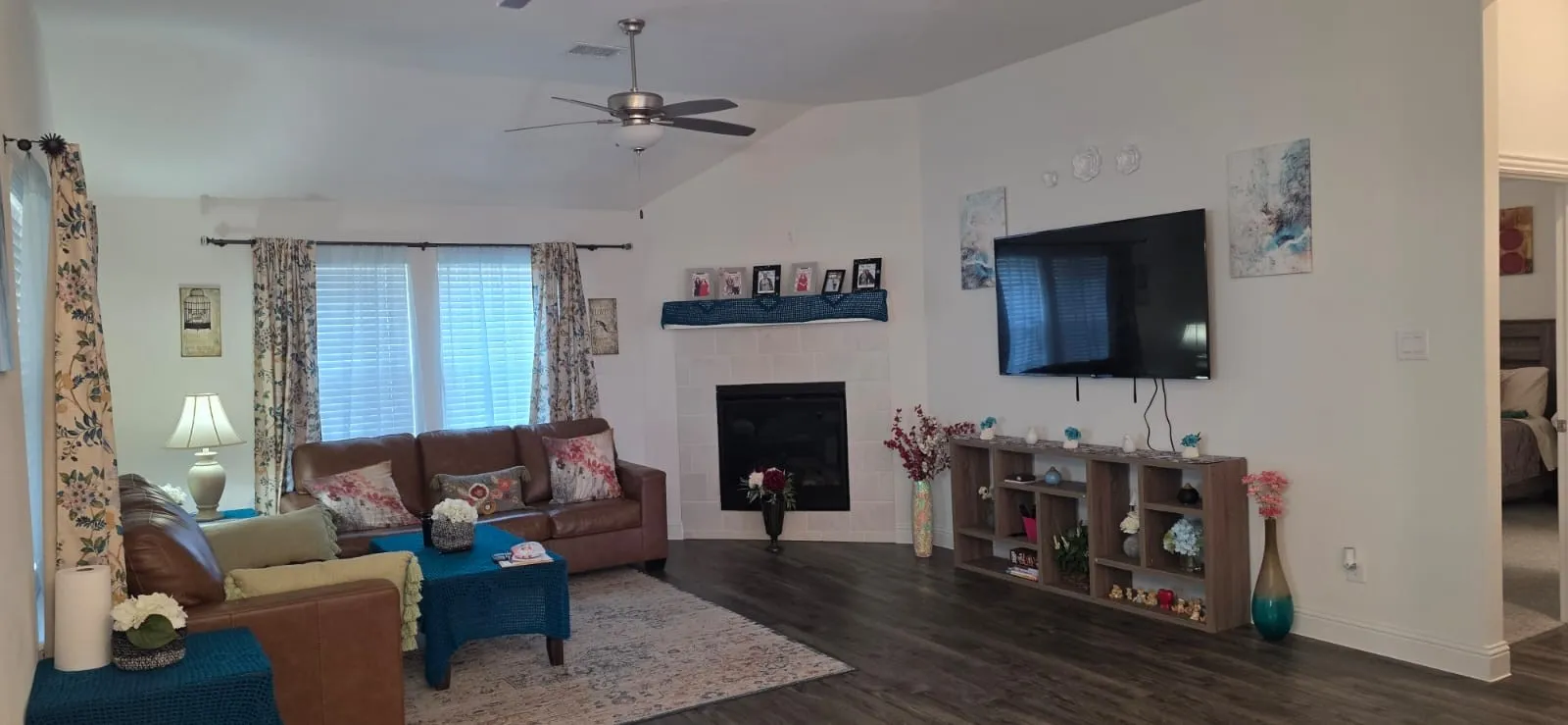 Vaulted ceiling featuring a ceiling fan, a fireplace with a mantel, wood-finish flooring, and white walls