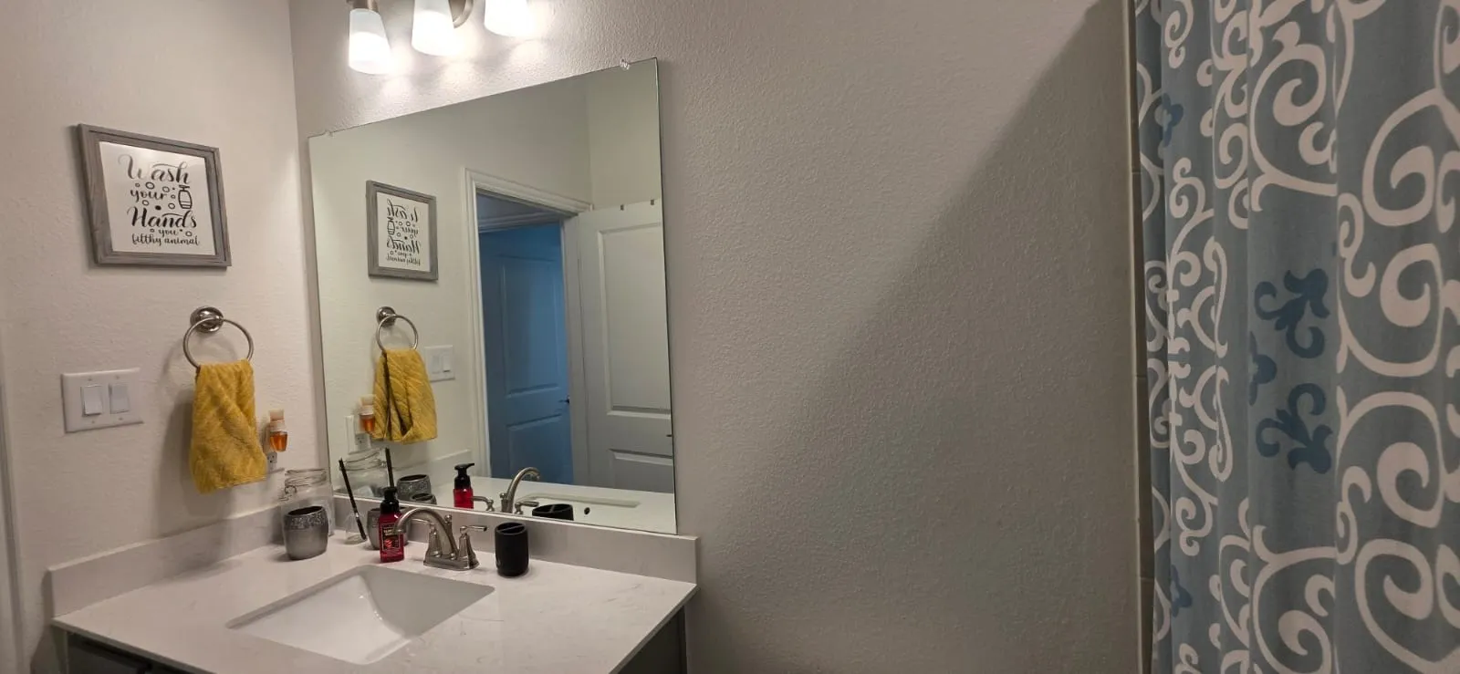 BATH 3 Wall-mounted light fixture, large vanity mirror, under-mount sink, chrome faucet, and integrated countertop