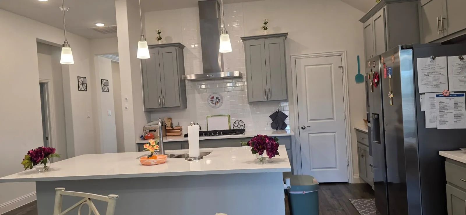 Kitchen featuring a large island with a light-colored countertop, gray cabinetry, stainless steel appliances, and pendant lighting