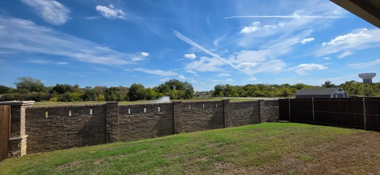 Expansive backyard featuring a stone retaining wall, level lawn space, and wood privacy fencing