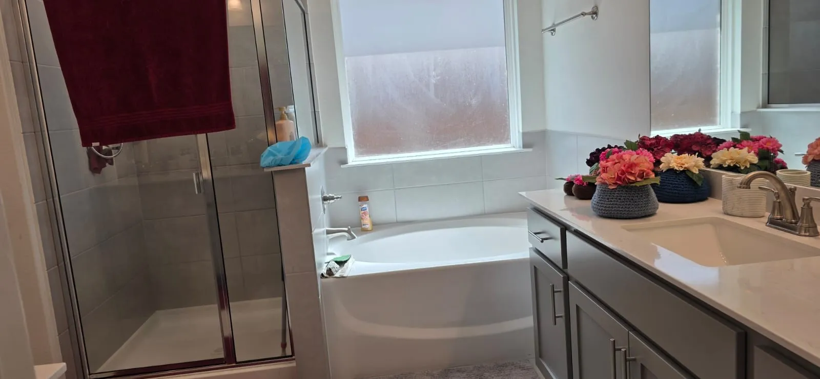 White countertop vanity with undermount sink, brushed nickel faucet, and gray cabinetry
