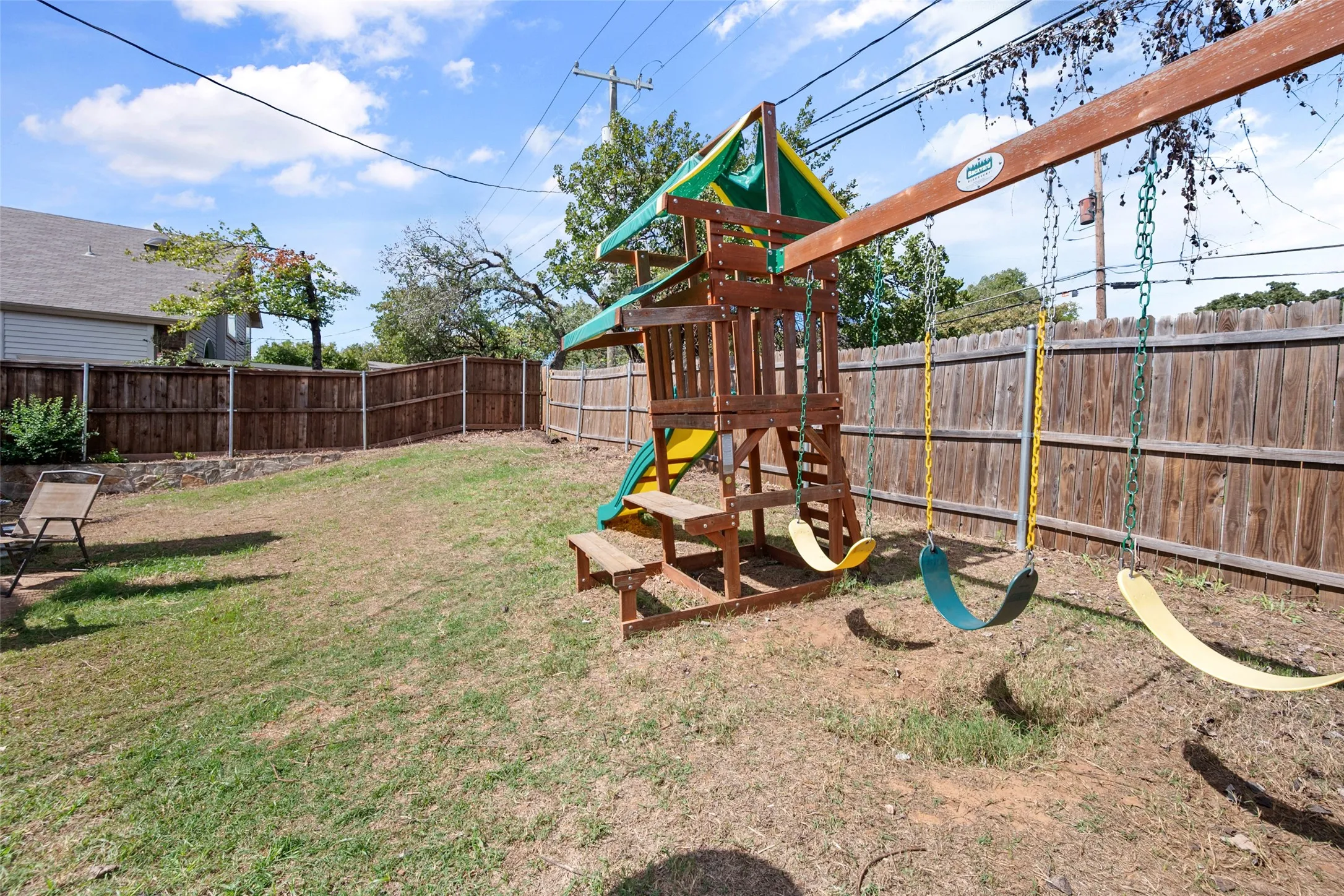 Backyard featuring a wood-plank perimeter fence and stone retaining wall