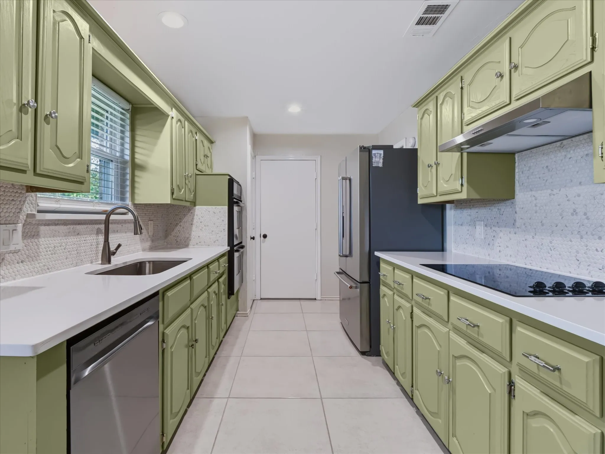 Kitchen featuring painted cabinetry, stainless steel appliances, solid surface countertops, mosaic tile backsplash, and tile flooring