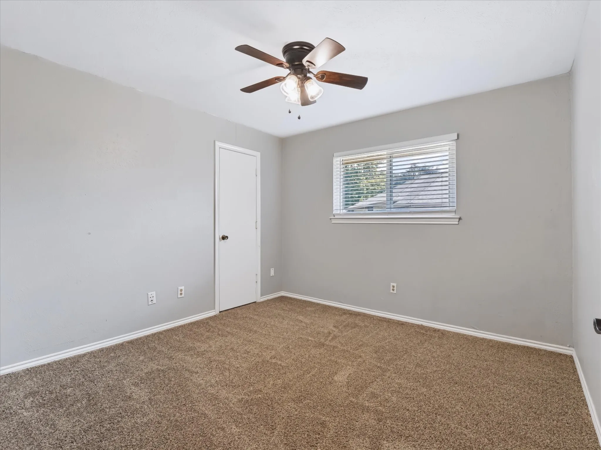 Room featuring neutral-toned carpeting, a ceiling fan with integrated lighting, and a horizontal window with adjustable blinds