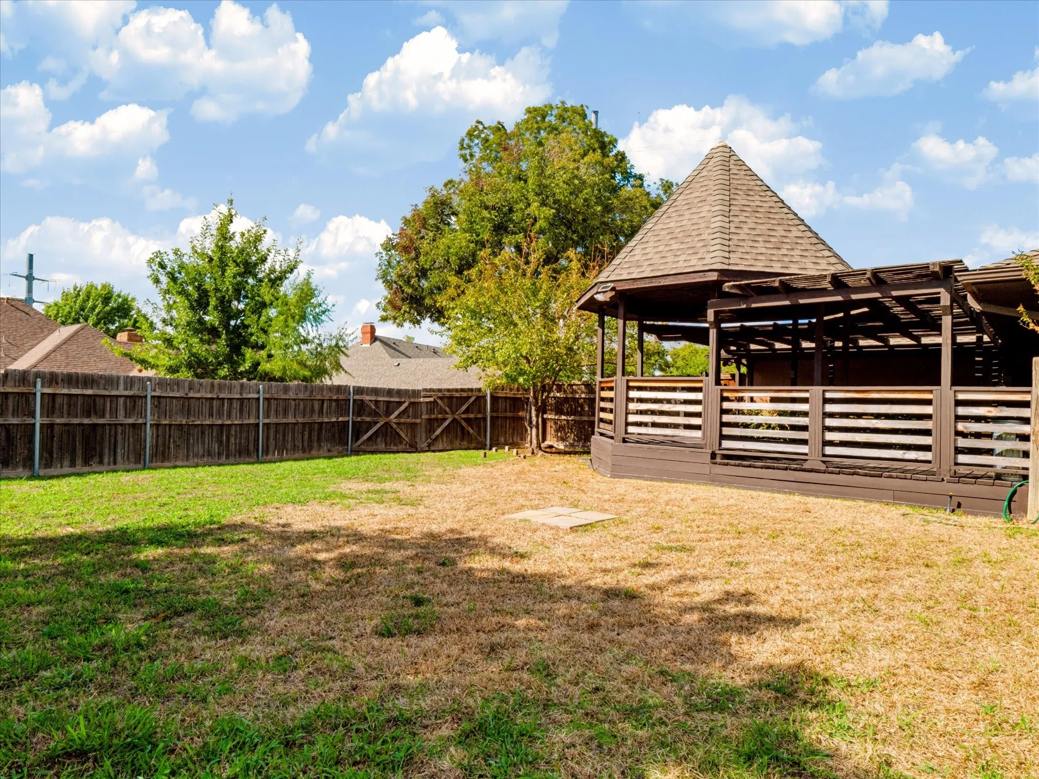 Backyard featuring a wood-frame gazebo, shingled roof, attached pergola, wood perimeter fencing, and mature trees
