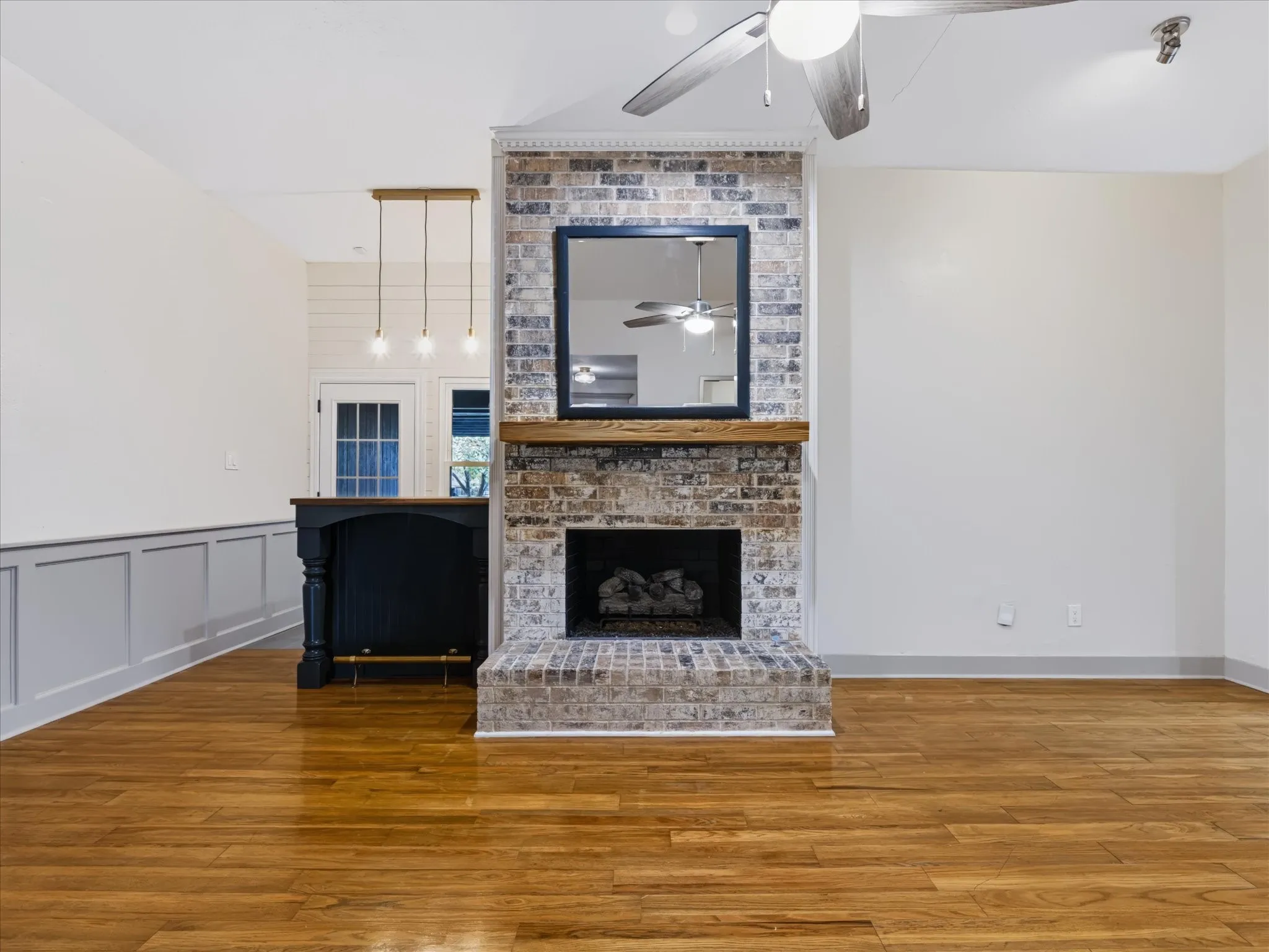 Fireplace with a brick surround, raised brick hearth, and heavy timber mantel