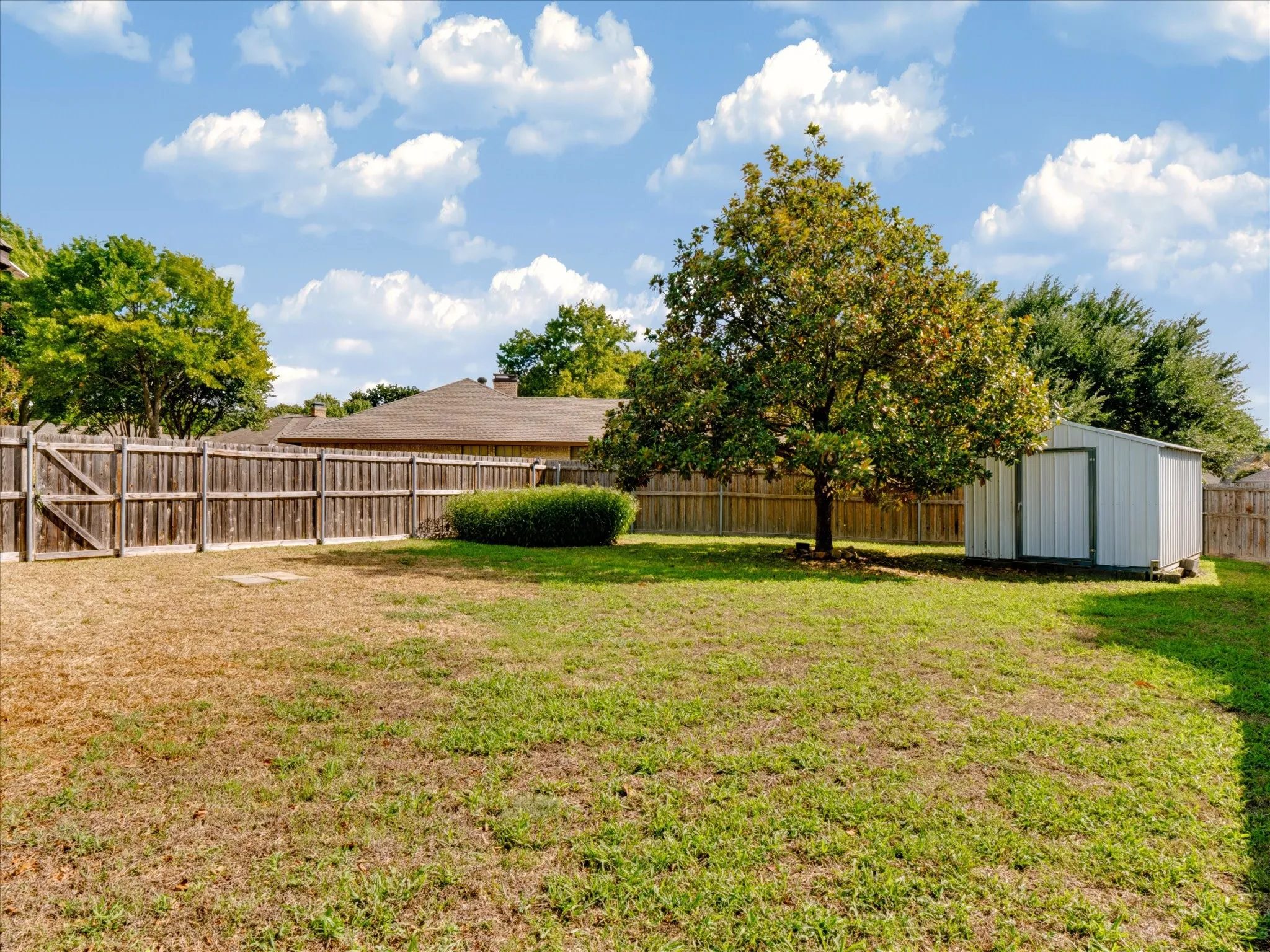 Backyard featuring a wood privacy fence, a detached storage structure, and mature landscaping