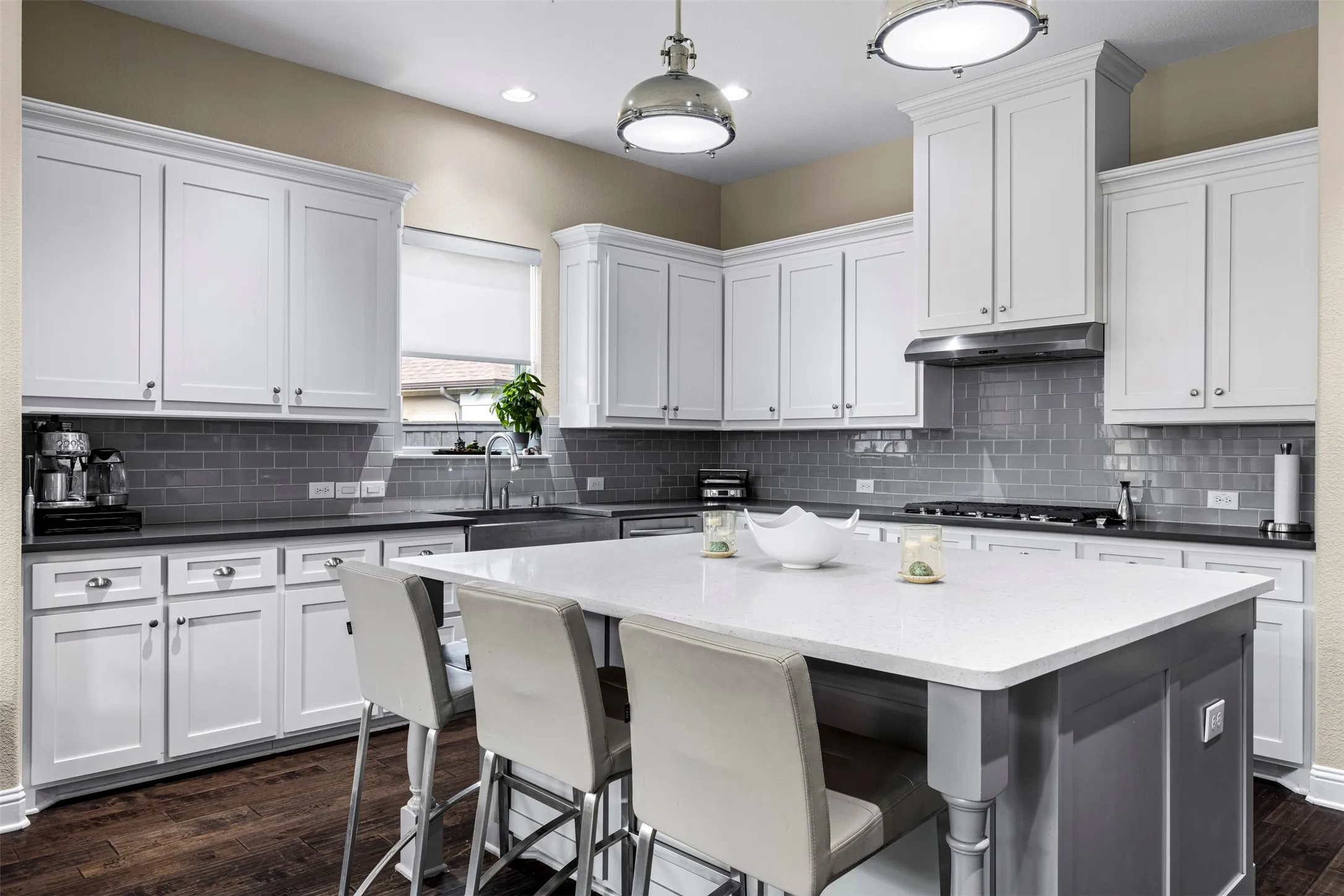 Kitchen featuring white cabinetry, center island with stone-finish countertop, stainless steel range hood, subway tile backsplash, and wood-finish flooring