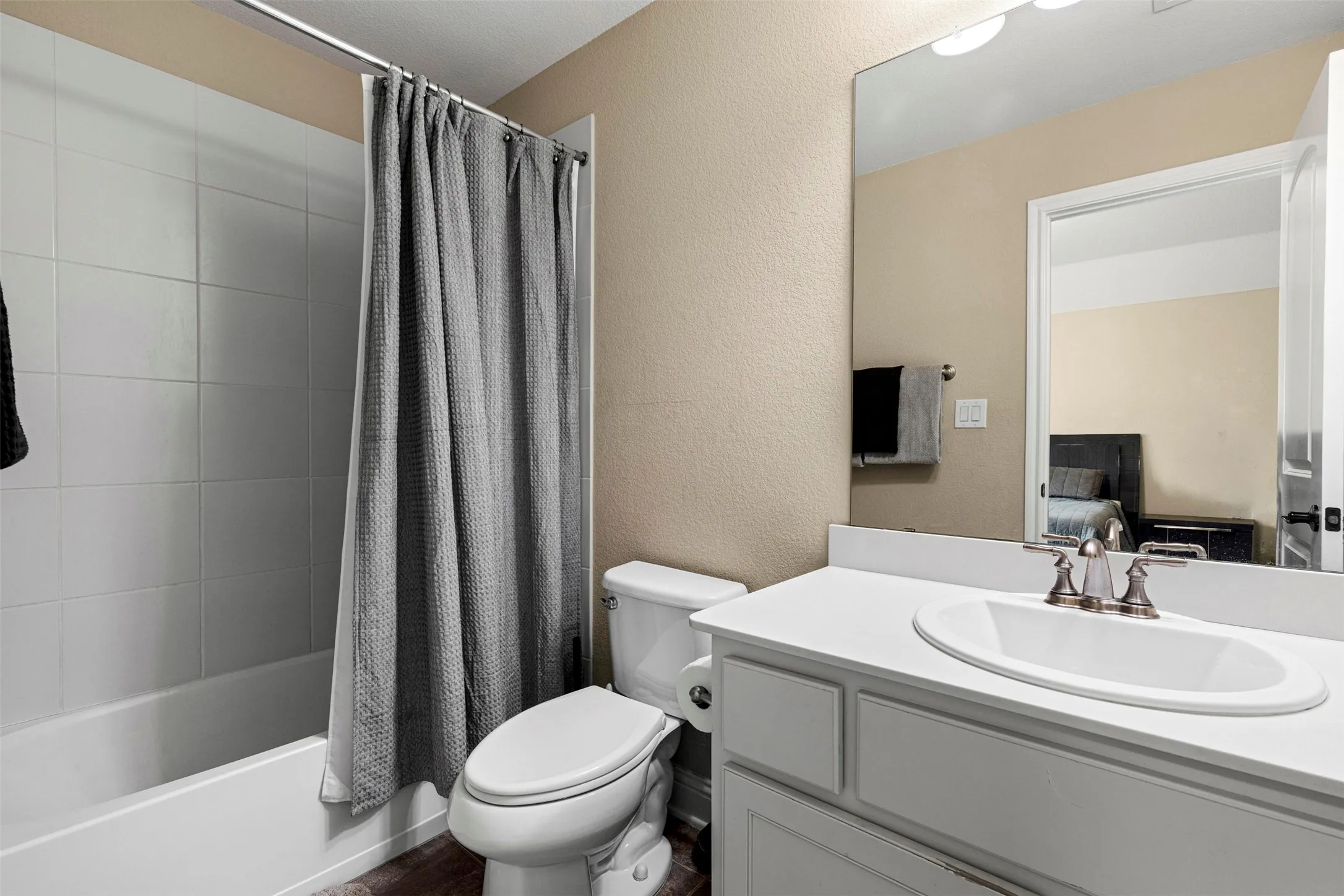 Bathroom featuring a white vanity with a composite countertop and integrated oval sink, large wall-mounted mirror, and tub-shower combination with square wall tile