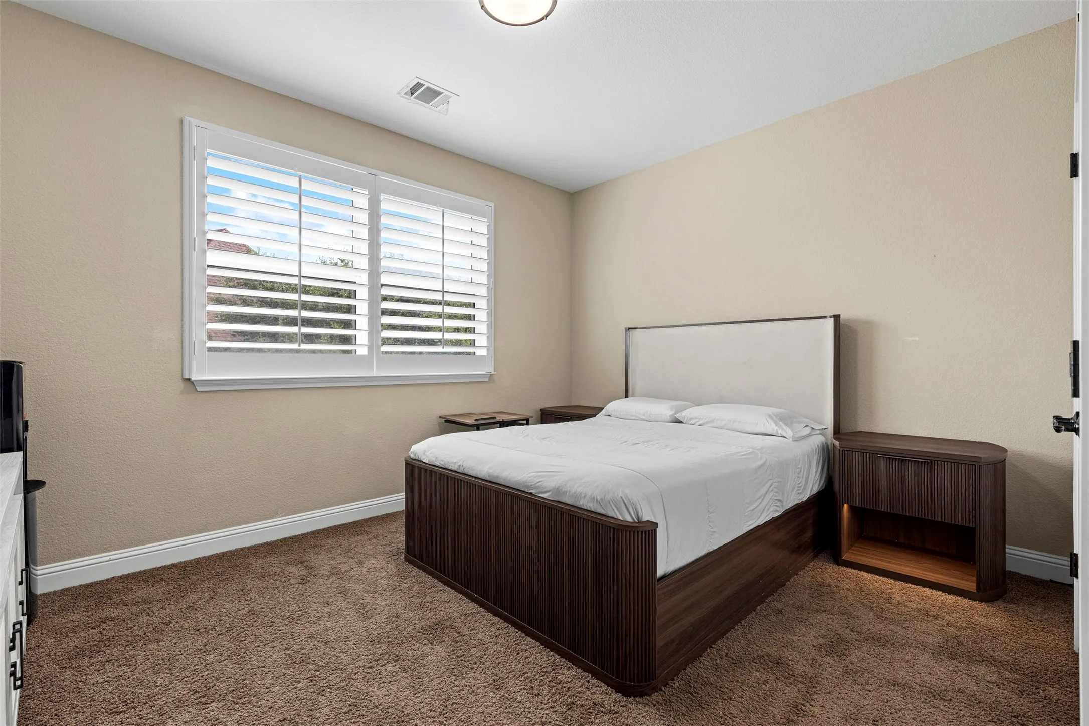 Neutral wall coloring, wall-to-wall carpeting, and window with plantation shutters