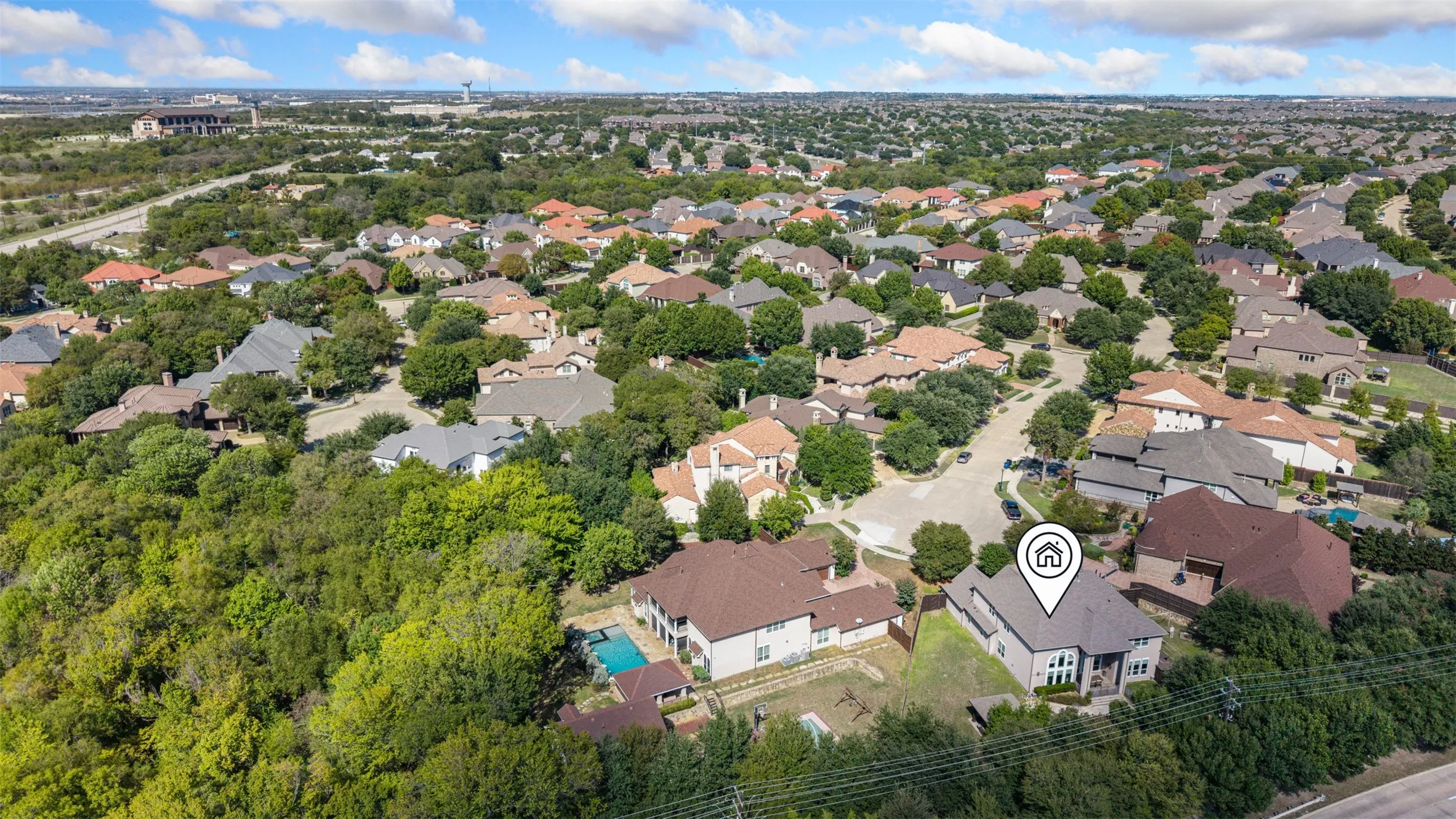 Aerial perspective of a multi-story residence featuring a multi-pitched roofline, stone and brick masonry exterior, and a secluded lot bordering extensive mature trees
