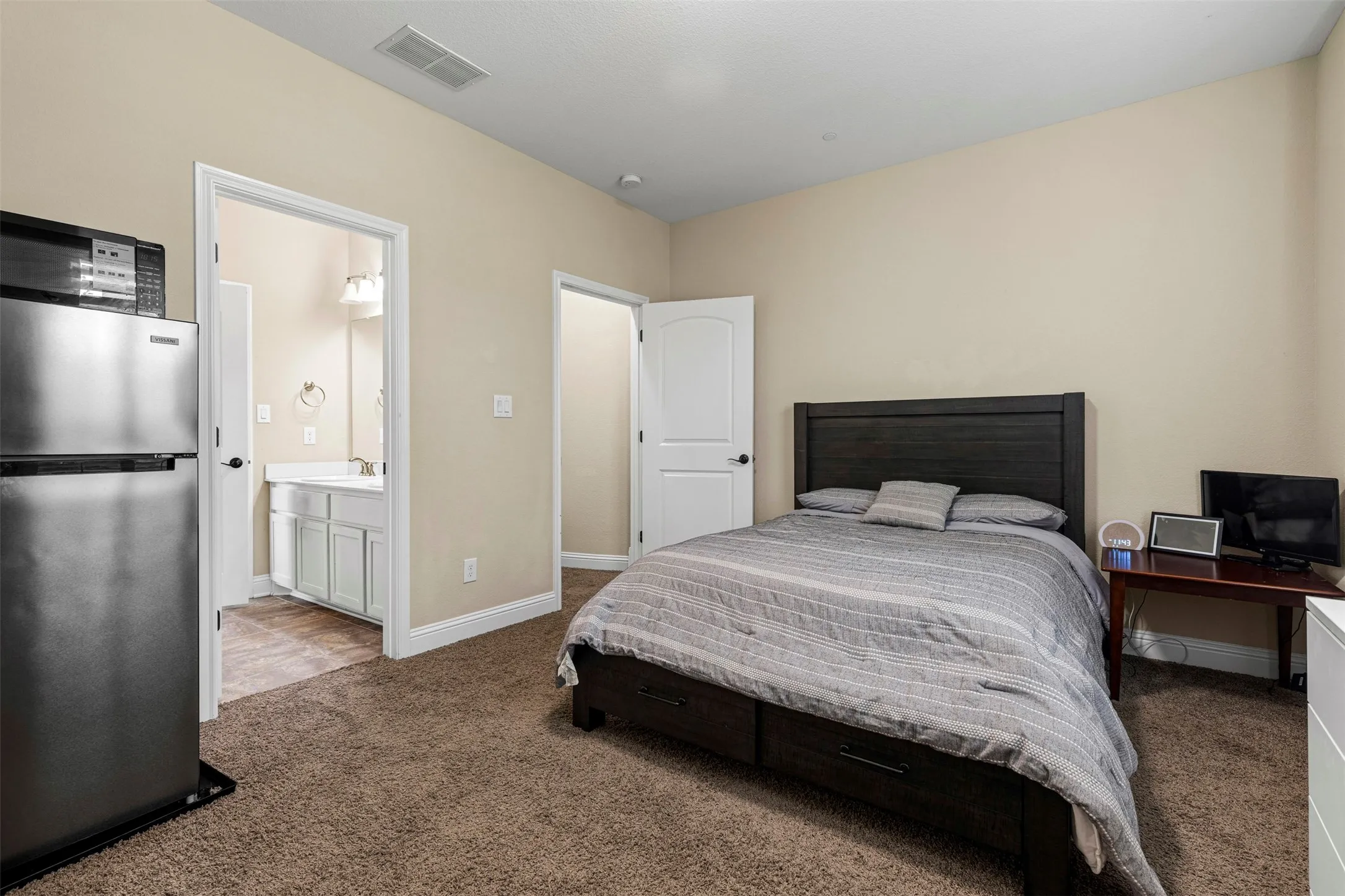 Interior space featuring wall-to-wall carpeting and an en-suite bathroom containing a vanity with integrated storage