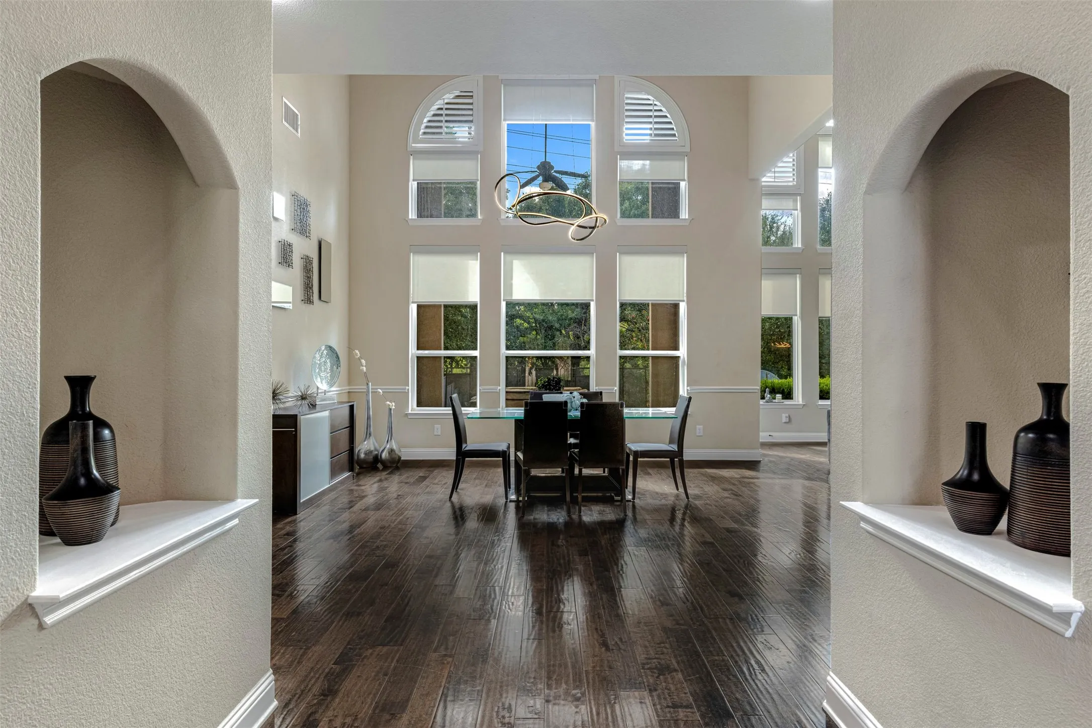 Expansive interior space featuring high ceilings, dark wood-finish flooring, dual built-in arched wall niches, and a multi-pane window configuration with arched top panels