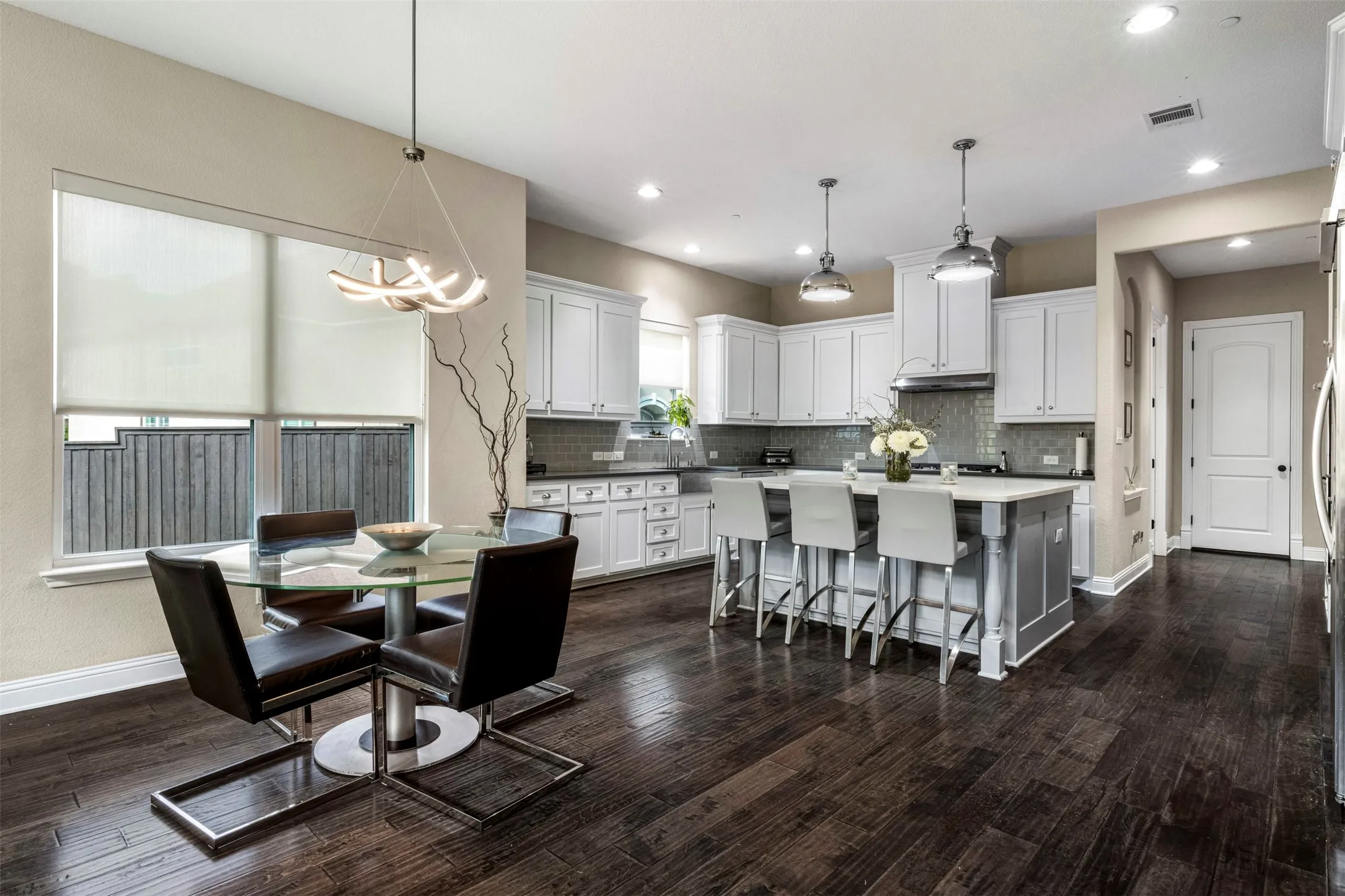 Kitchen featuring wood-finish flooring, white cabinetry, a center island with stone countertop, stainless steel range hood, and recessed lighting