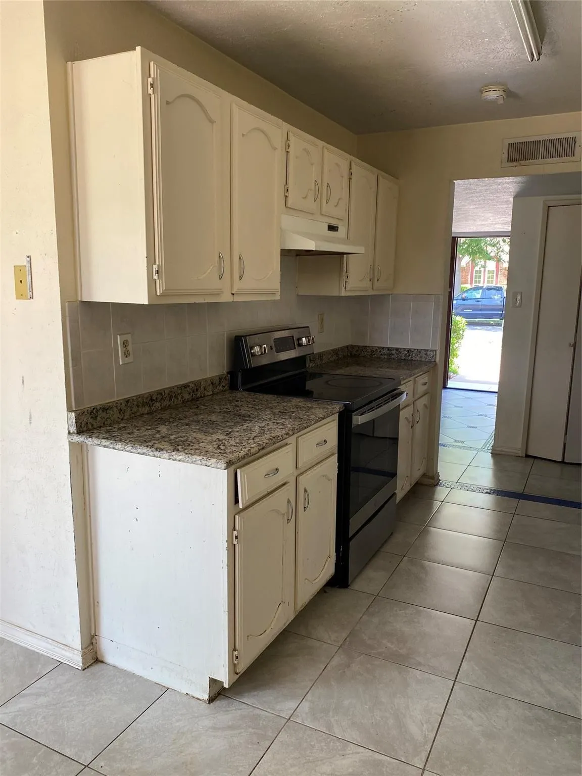 Kitchen featuring painted cabinetry, stone-finish countertops, tiled backsplash, and ceramic tile flooring