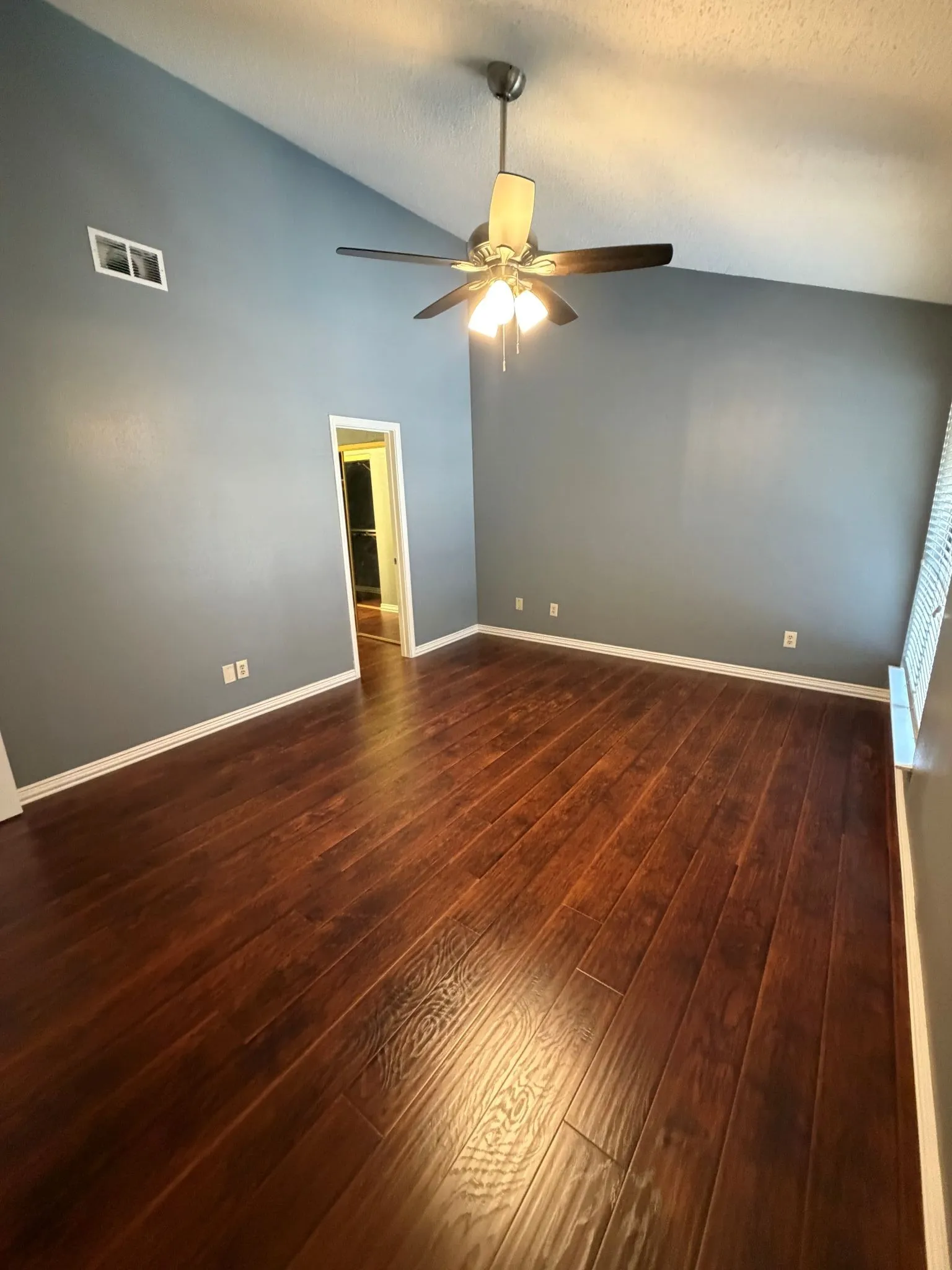 Vaulted ceilings, primary bedroom upstairs wood-finish flooring, and a central ceiling fan with integrated light fixture