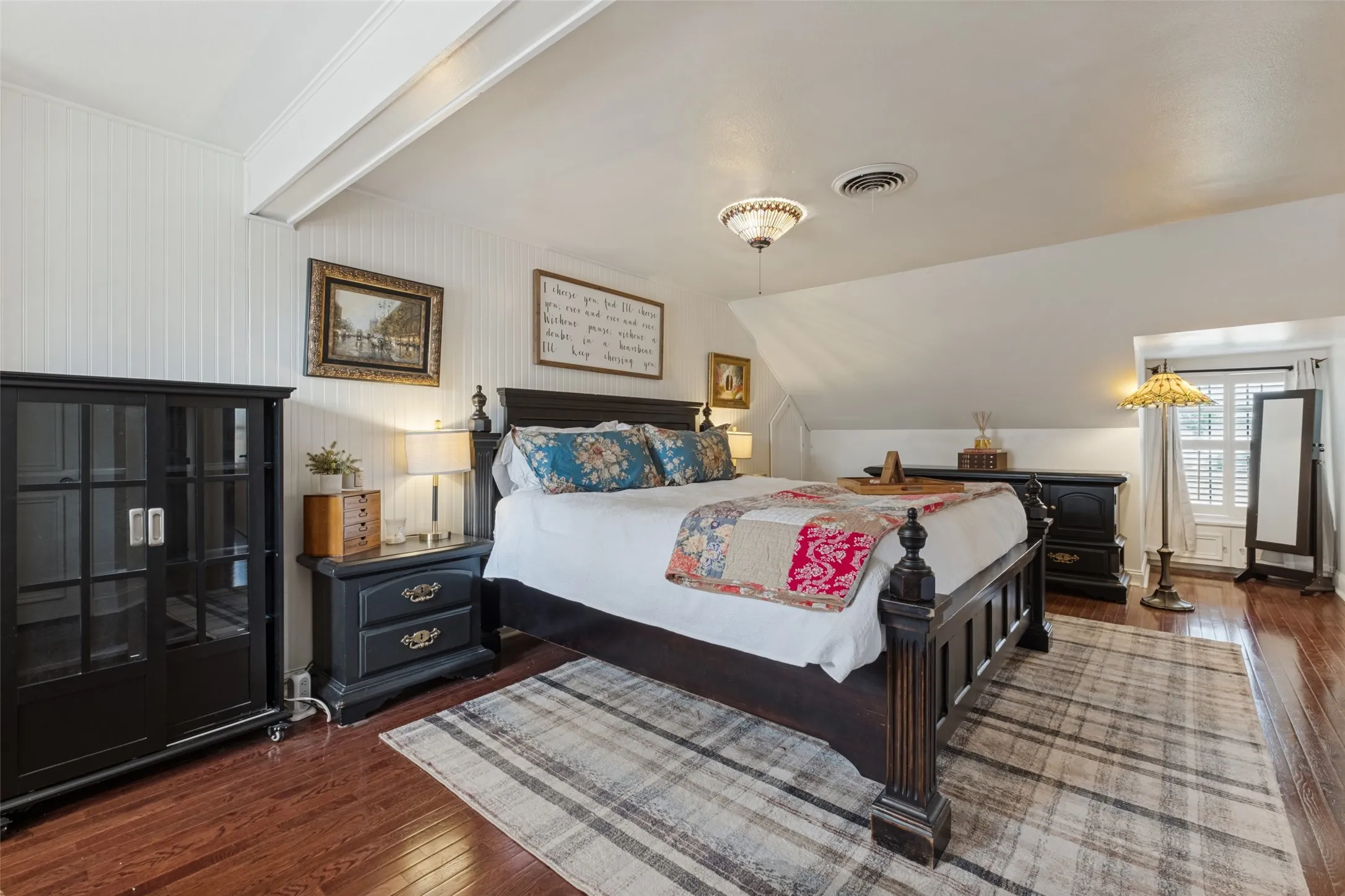 Beadboard wall paneling, wood-finish flooring, and dormer window featuring plantation shutters