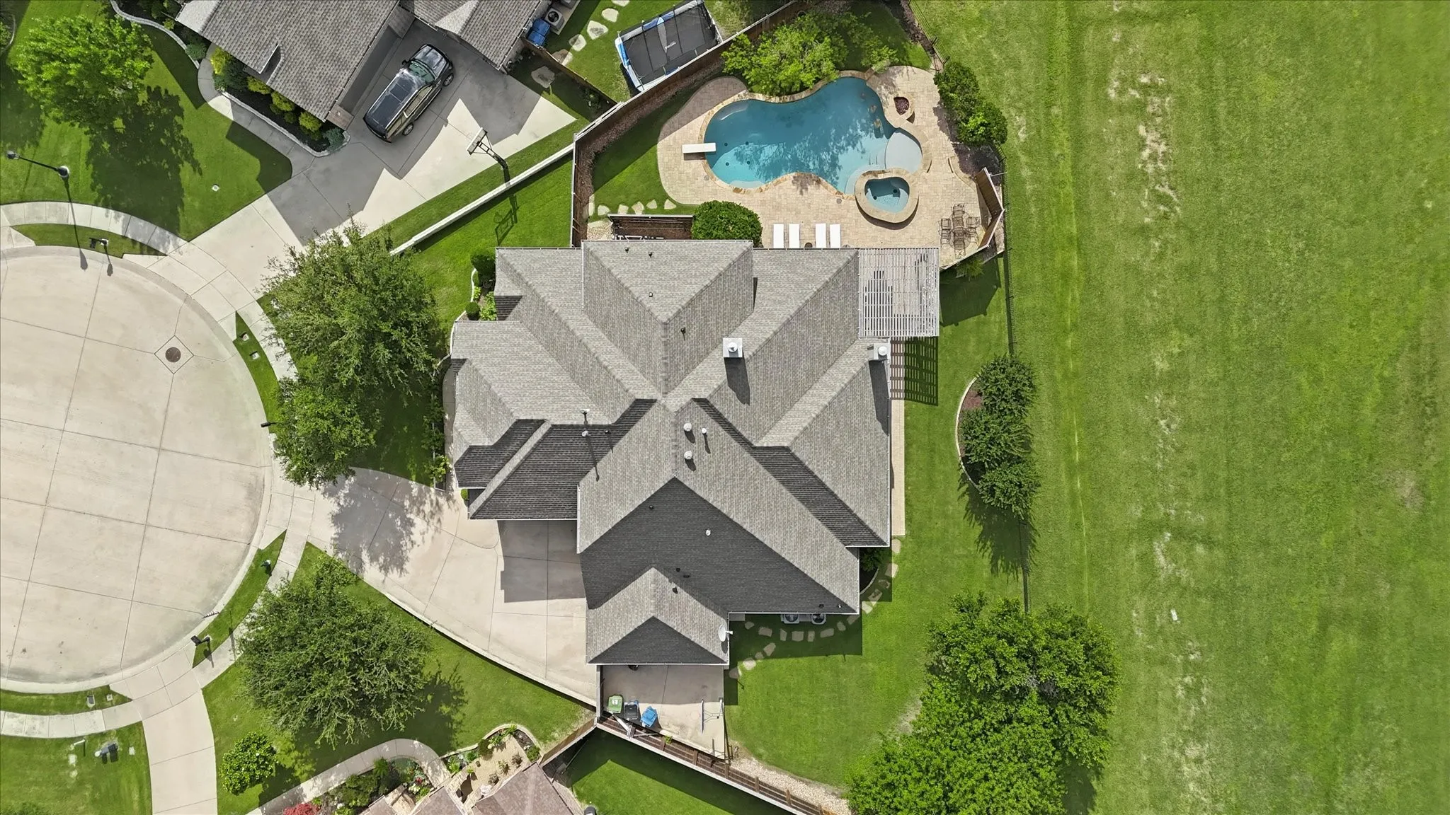 Aerial perspective of a property featuring an in-ground pool with attached spa, concrete patio, pergola, and fenced grounds