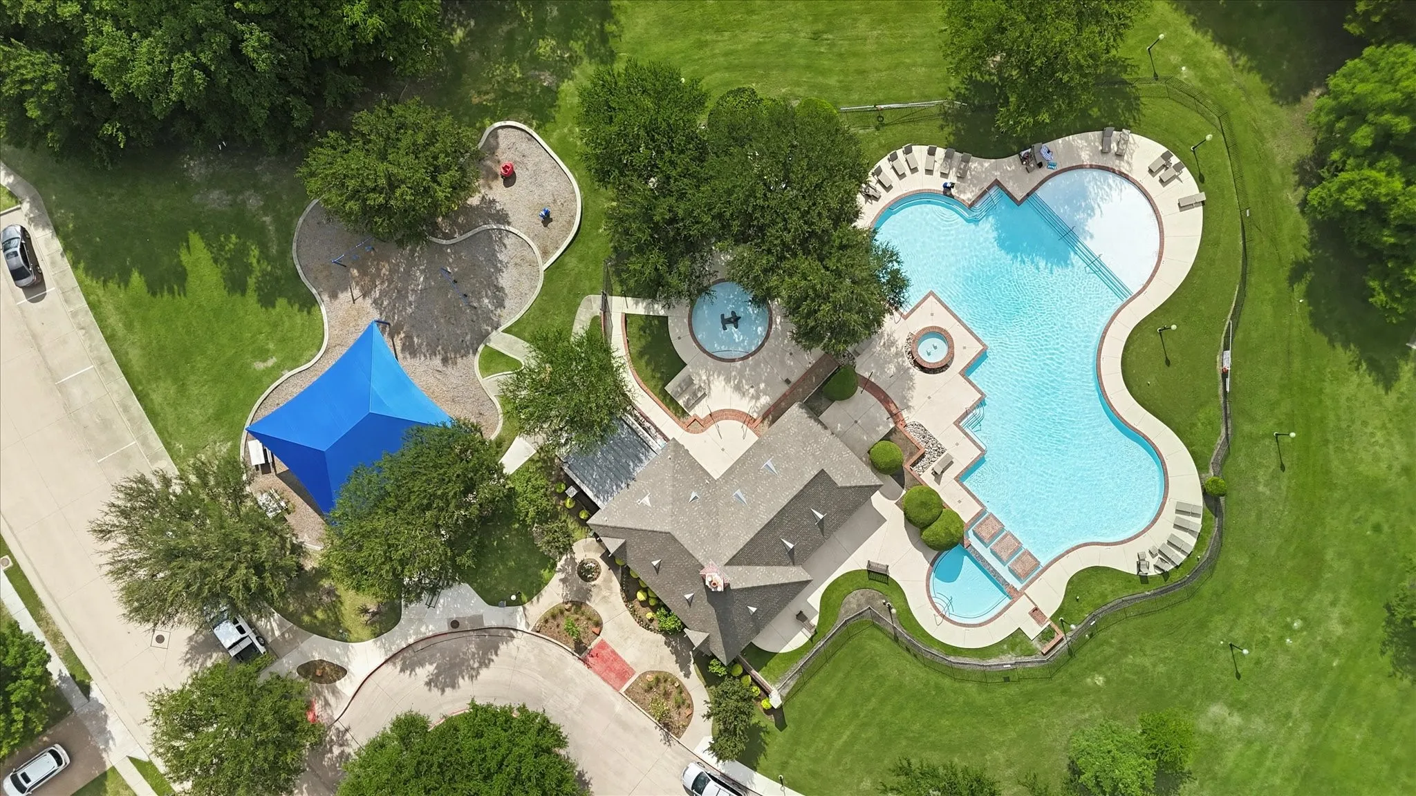 Community recreation area featuring a swimming pool with spa, sun deck, shaded pavilion, and playground