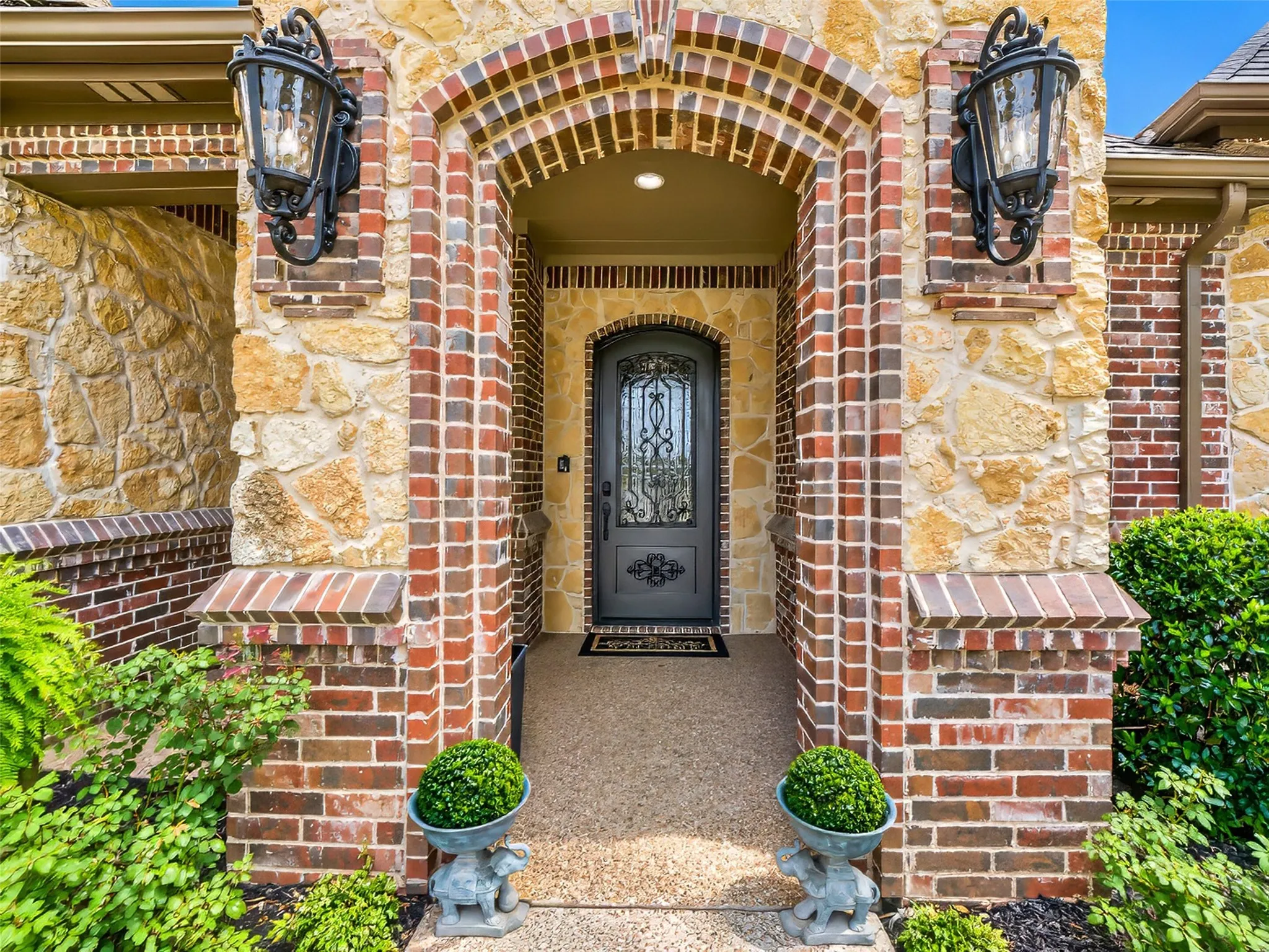 Stately stone and brick facade with custom iron front entry door.