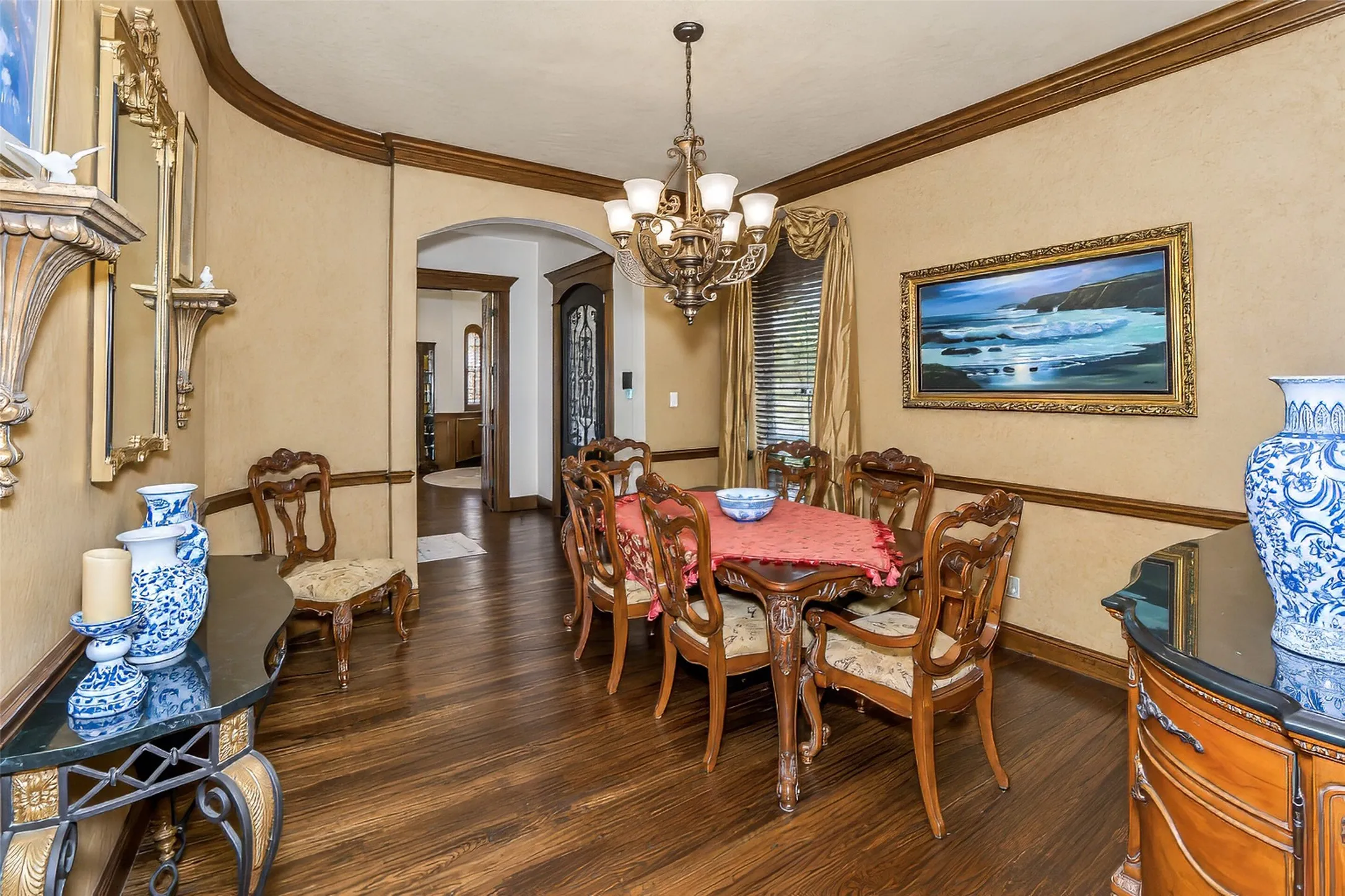 Beautifully appointed formal dining with extensive millwork, chandelier and custom drapery.