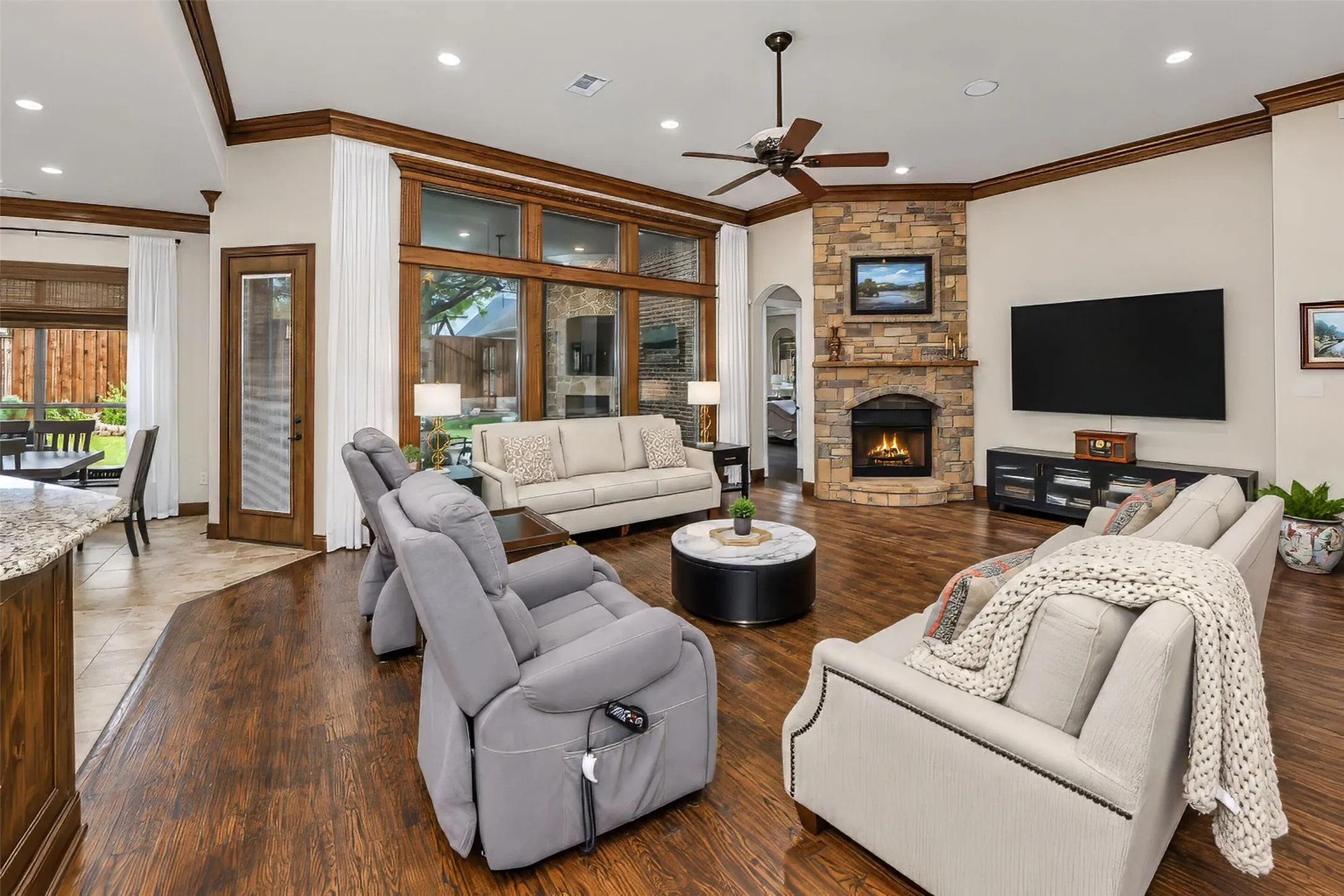 Great room with wood flooring and a wall of windows looking out over the back yard.