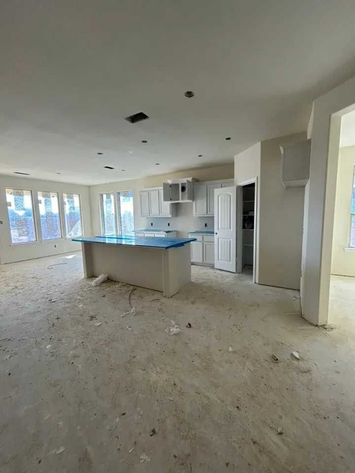 Open-concept living area featuring a kitchen island, white cabinetry, and multiple windows along the rear wall
