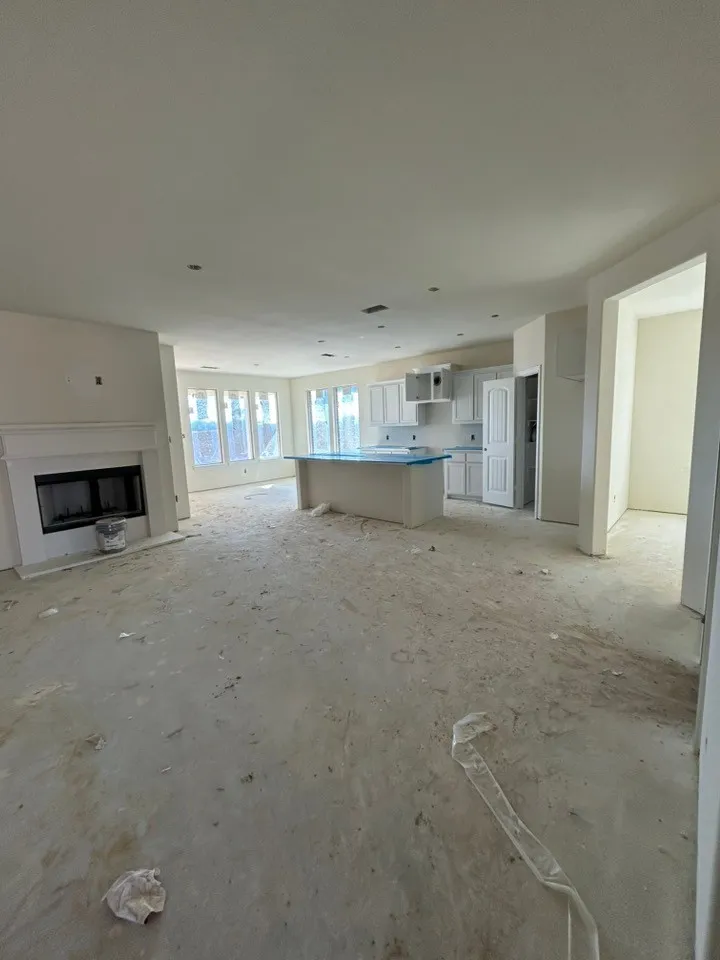 Expansive open-concept space featuring a white kitchen island, white cabinetry, and a fireplace with a white mantel