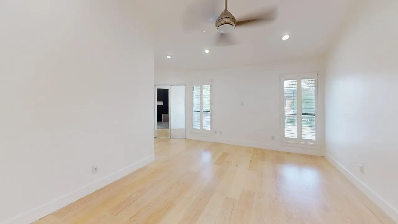Light-filled interior featuring wood-finish flooring, recessed lighting, a ceiling fan, dual-panel interior shutters, and mirrored closet doors