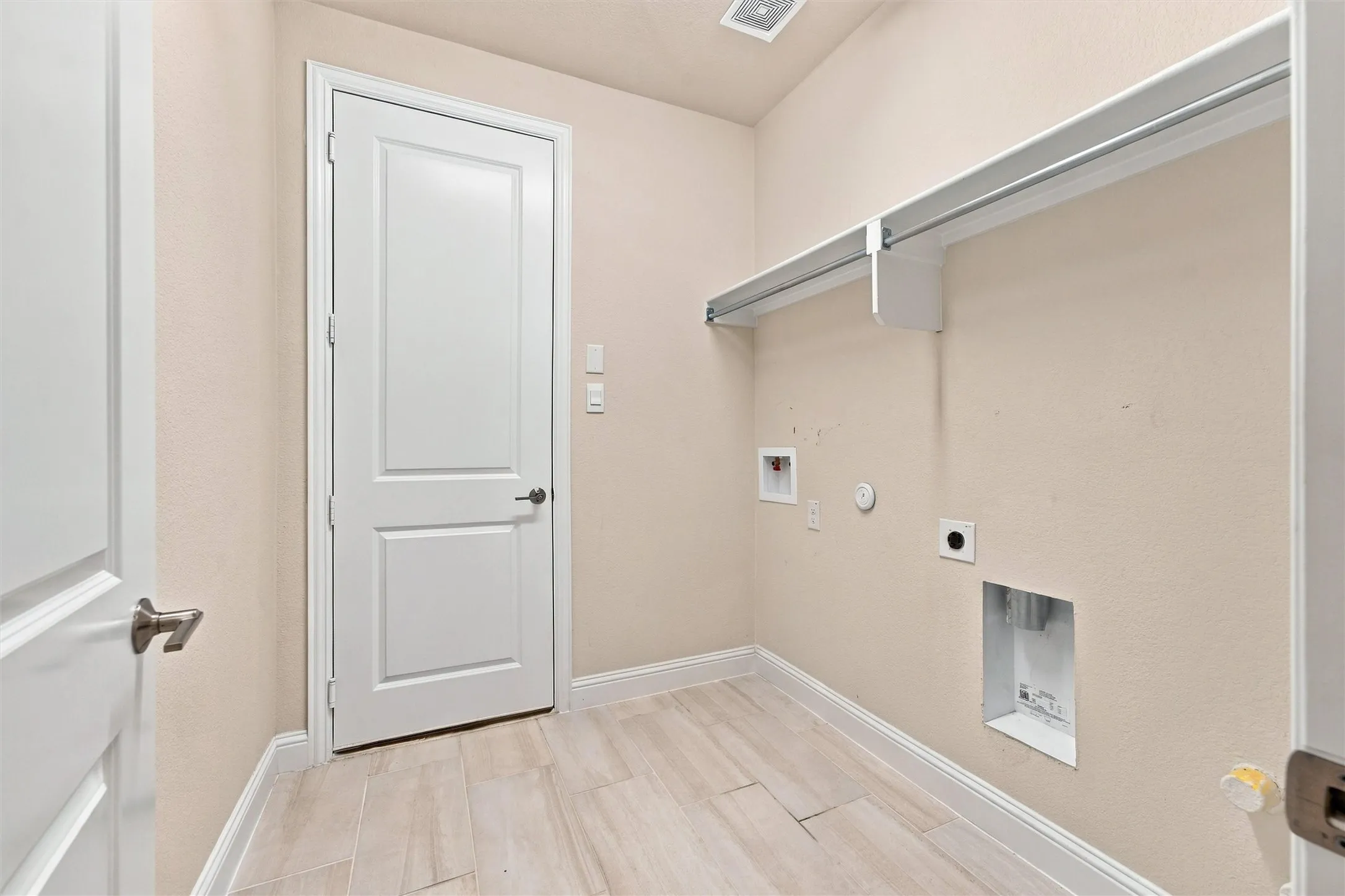 Utility room featuring wood-finish tile flooring, white two-panel interior doors, and built-in overhead shelving