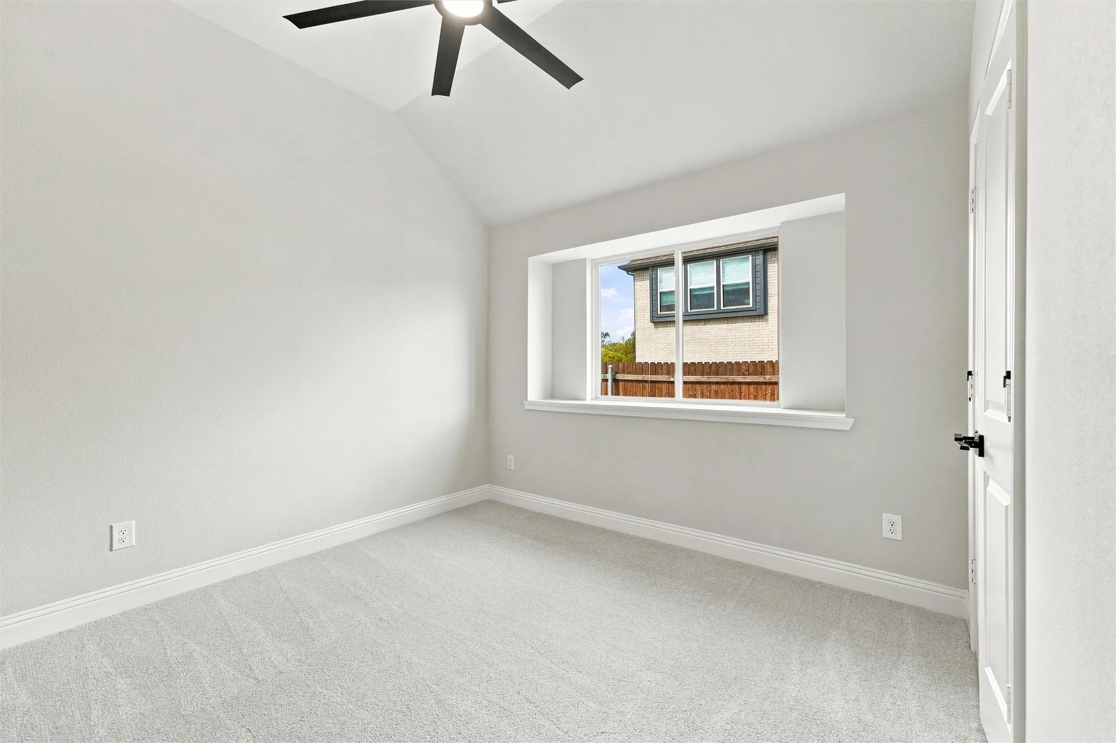 Vaulted ceiling, carpeted flooring, inset window with sill, and matte black ceiling fan with integrated light