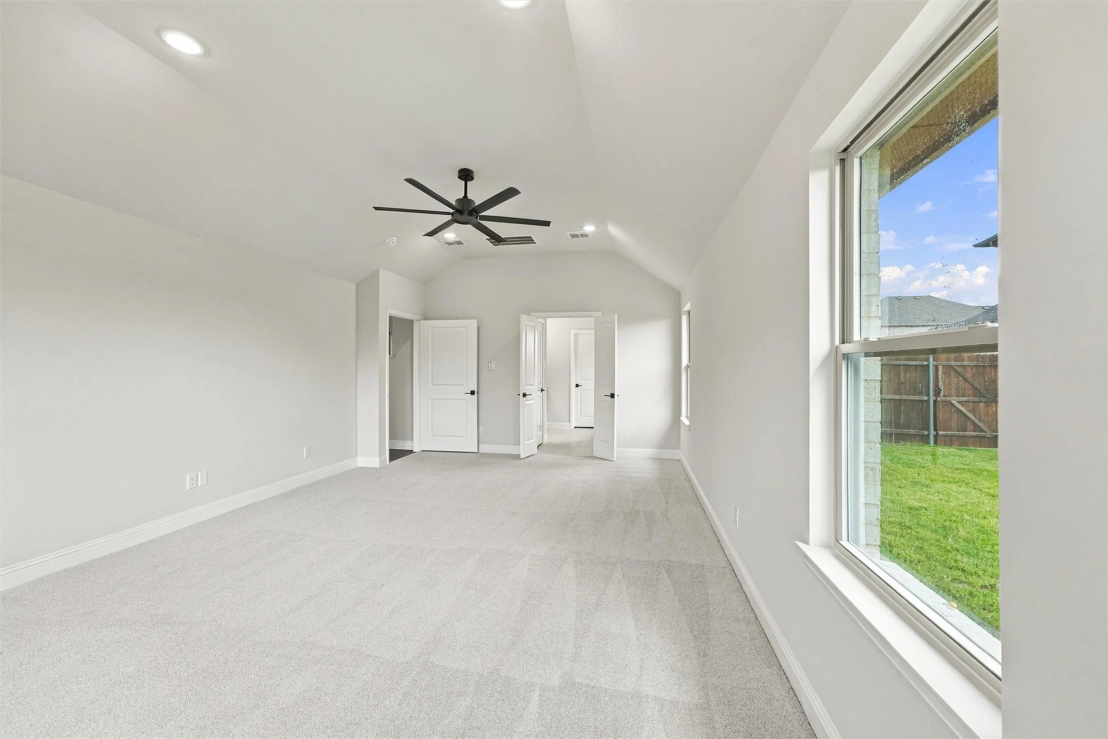 Vaulted ceilings featuring recessed lighting and a matte black ceiling fan, complemented by carpeting and large windows