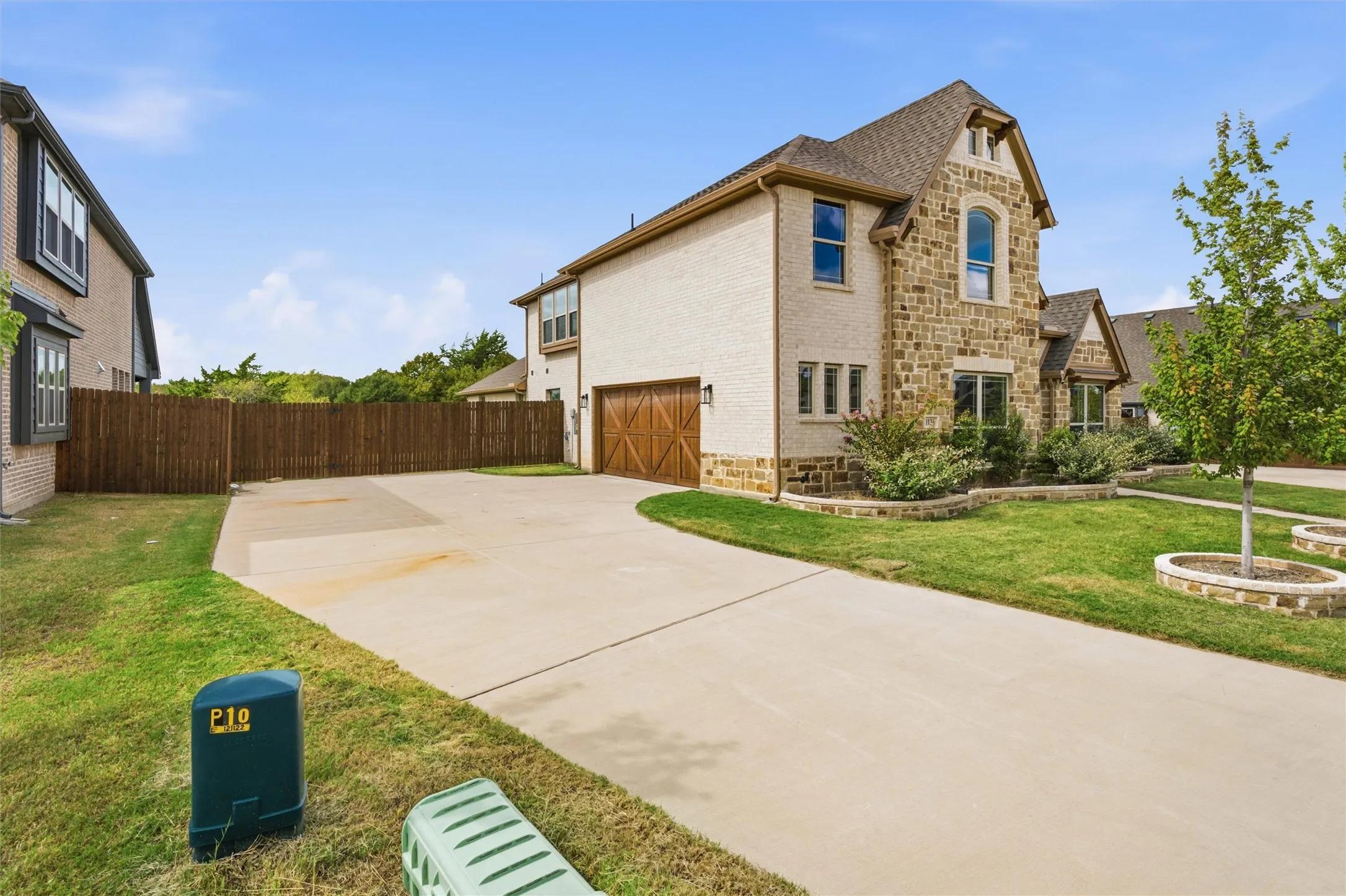 Two-story exterior featuring masonry stone veneer, light-colored brick siding, and an attached multi-car garage with wood-finish doors