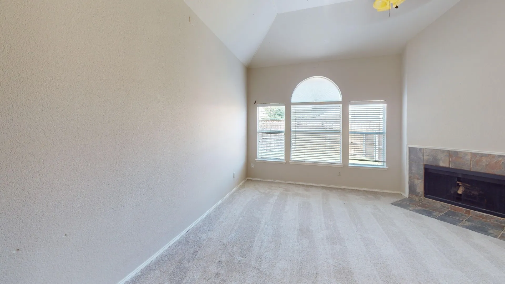 Vaulted ceiling, arched picture window, and tile-surround fireplace with hearth