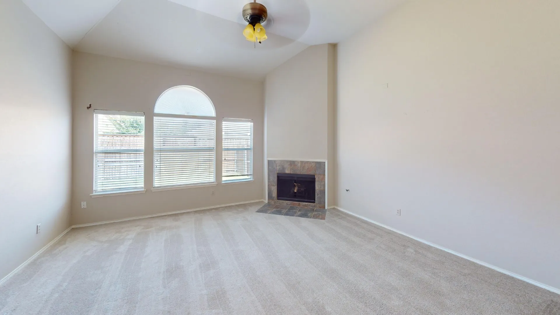 Vaulted ceilings, a stone-surround fireplace, and an arched window configuration featuring multiple panes