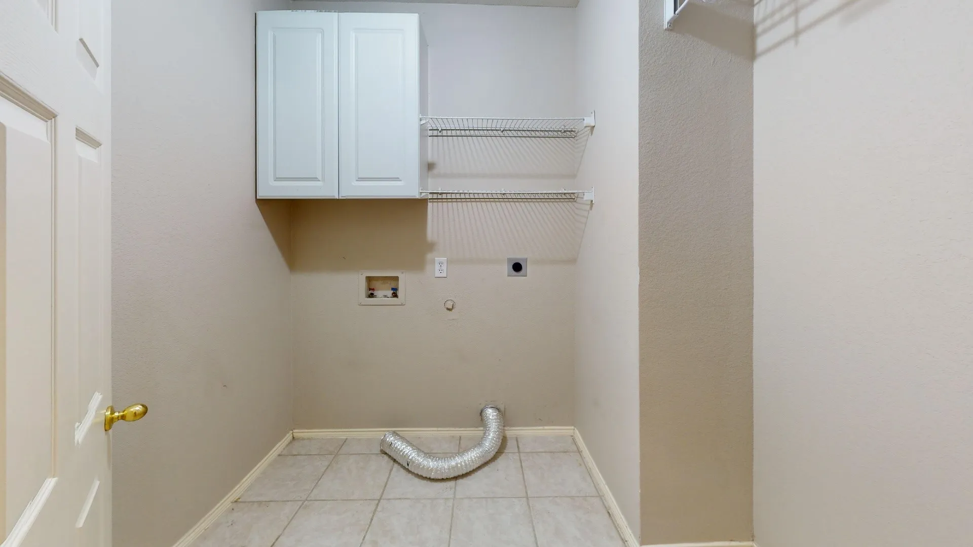 Laundry area featuring tile flooring, white shaker-style wall cabinetry, and dual wire shelving units