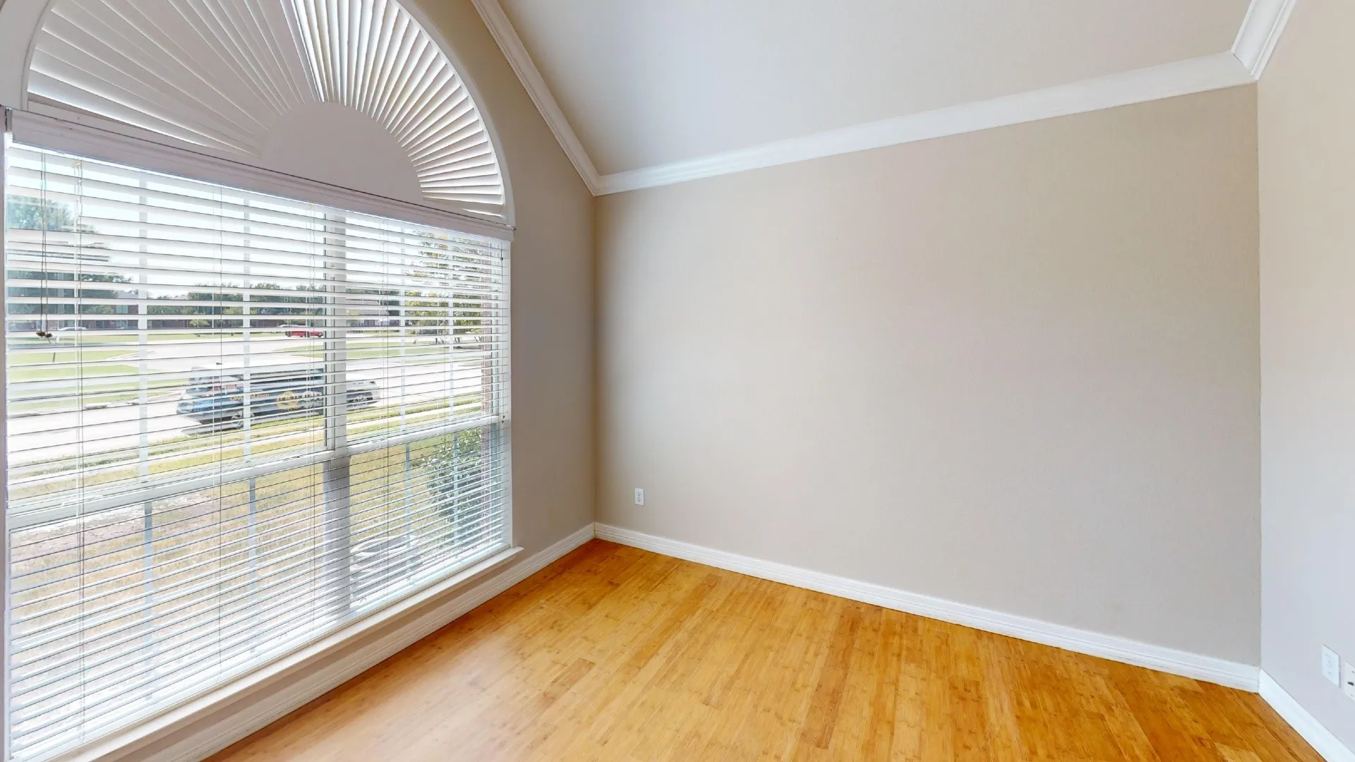 Vaulted ceiling featuring crown molding, wood-finish flooring, and a large arched window with horizontal blinds