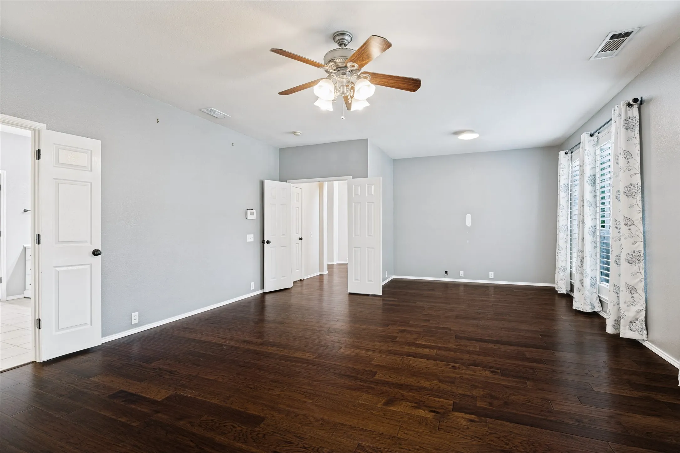 Primary bedroom with engineered wood flooring, plantation shutters, and flex space