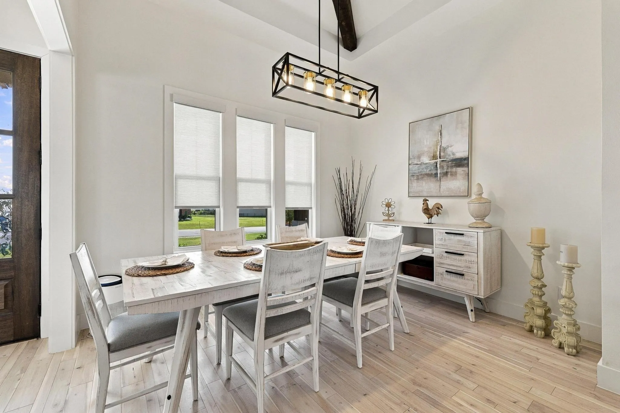Dining space featuring wood-finish flooring, vaulted ceilings with exposed wood beam, and a linear black metal chandelier