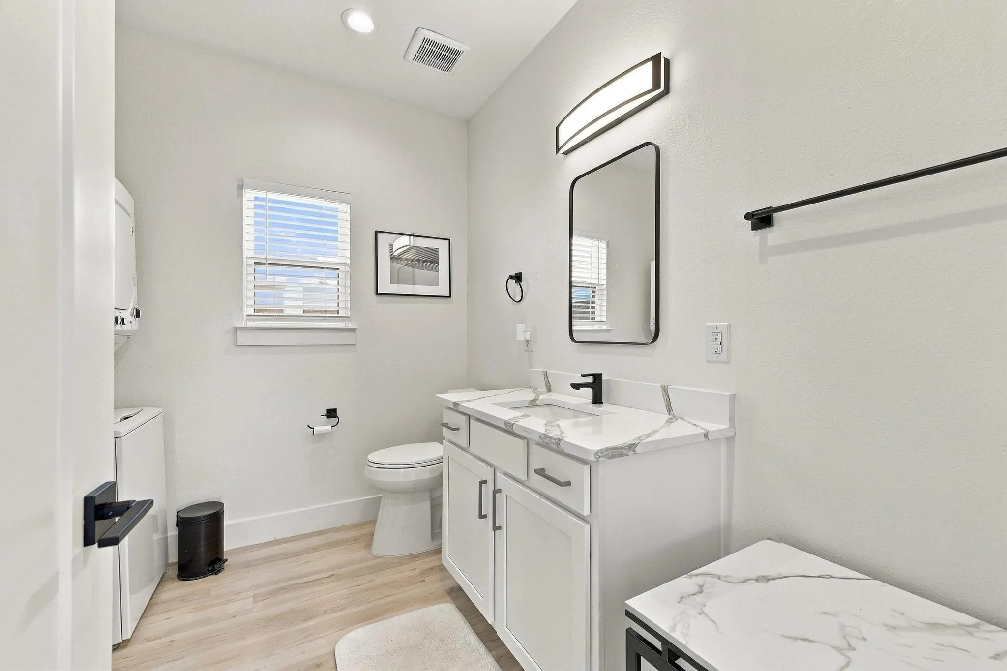 Neutral-toned bathroom featuring a vanity with a white composite countertop, undermount sink, matte black faucet, and matching black wall-mounted towel bar