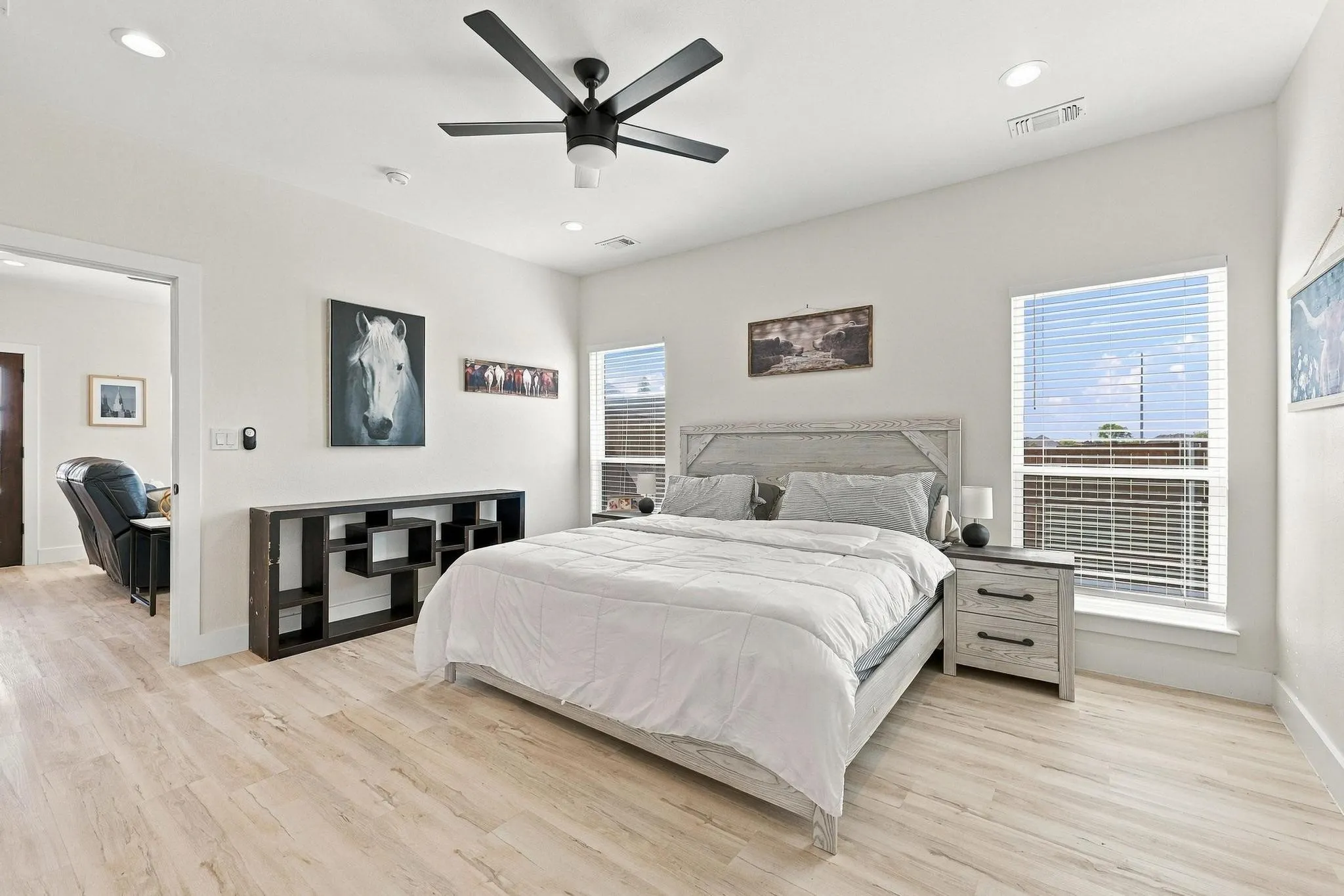 Light-toned wood-finish flooring, recessed lighting, and a dark-finish ceiling fan, complemented by dual windows with integrated blinds