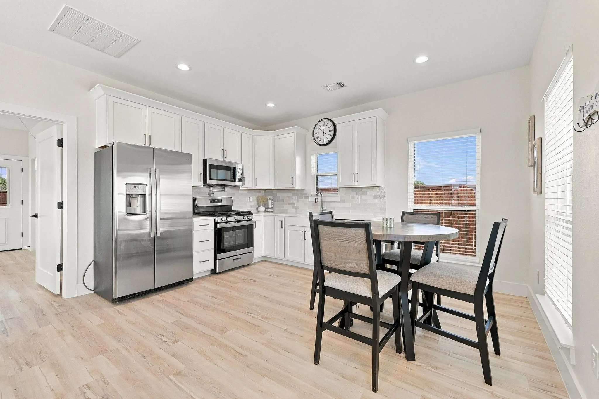 Kitchen featuring white shaker-style cabinetry, stainless steel appliances, light-toned wood-finish flooring, and recessed lighting