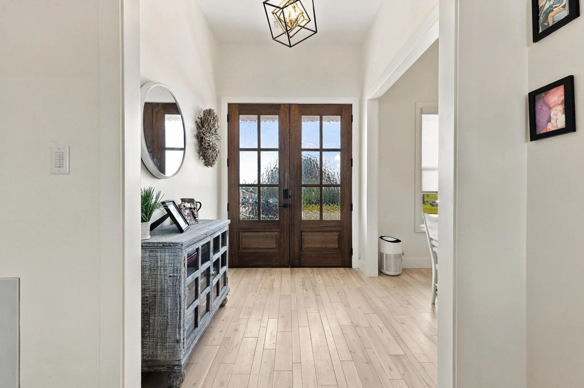 Foyer featuring double entry doors with glass panes, wood-finish flooring, and a geometric pendant light fixture