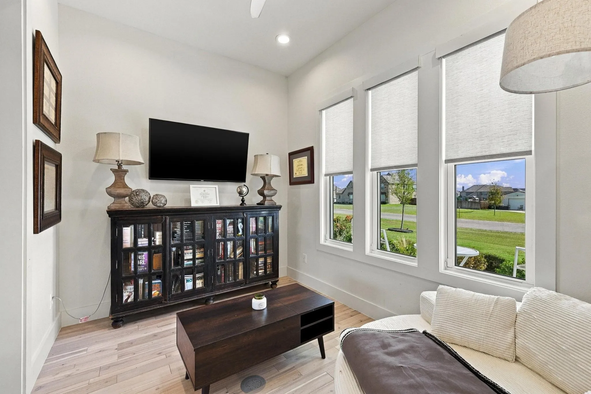 Light-filled interior space featuring high ceilings, three large windows with roller shades, and light-toned wood-finish flooring