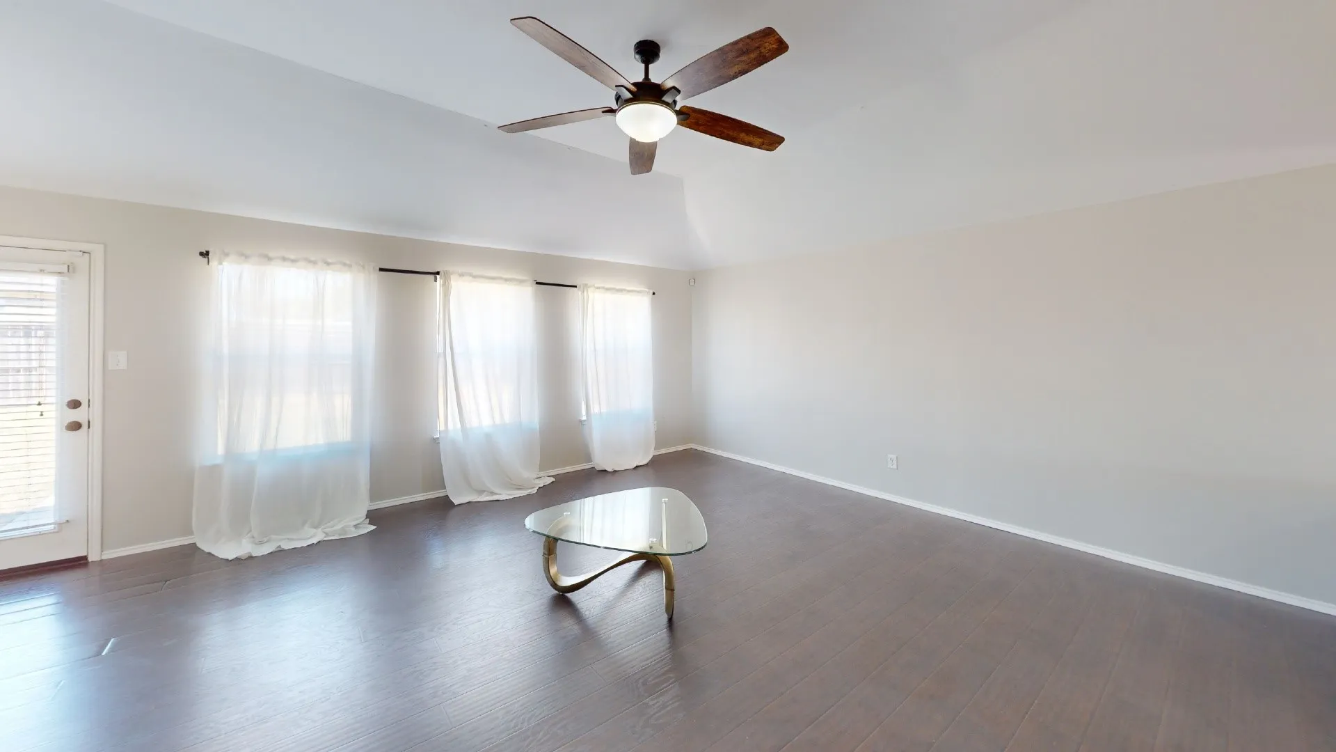 Vaulted ceilings, wood-finish flooring, and a central ceiling fan with integrated lighting