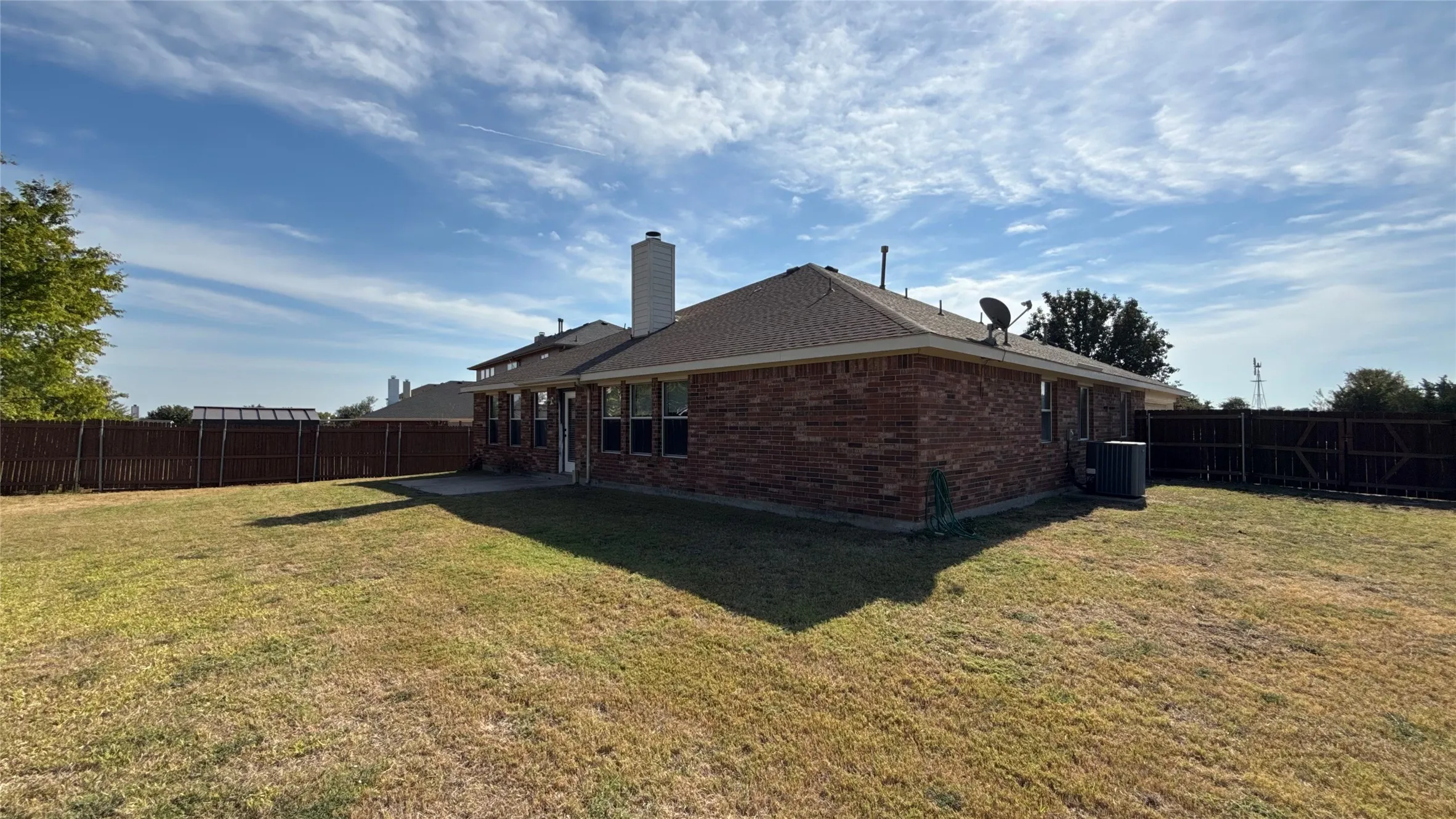 Brick exterior residence featuring a concrete patio, exterior chimney, and a fenced backyard