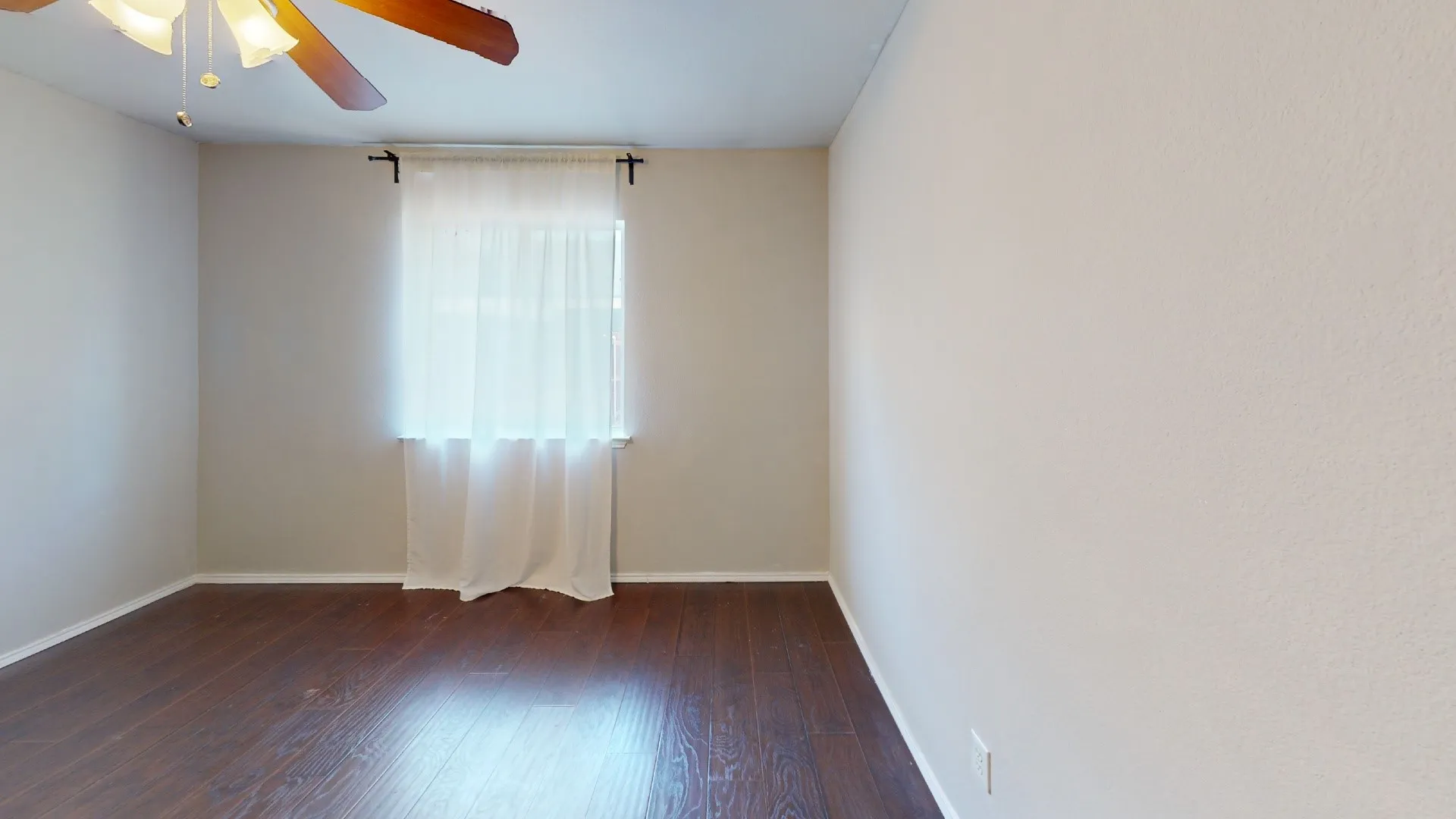 Room featuring wood-finish flooring, neutral wall paint, and a ceiling-mounted fan with integrated lighting