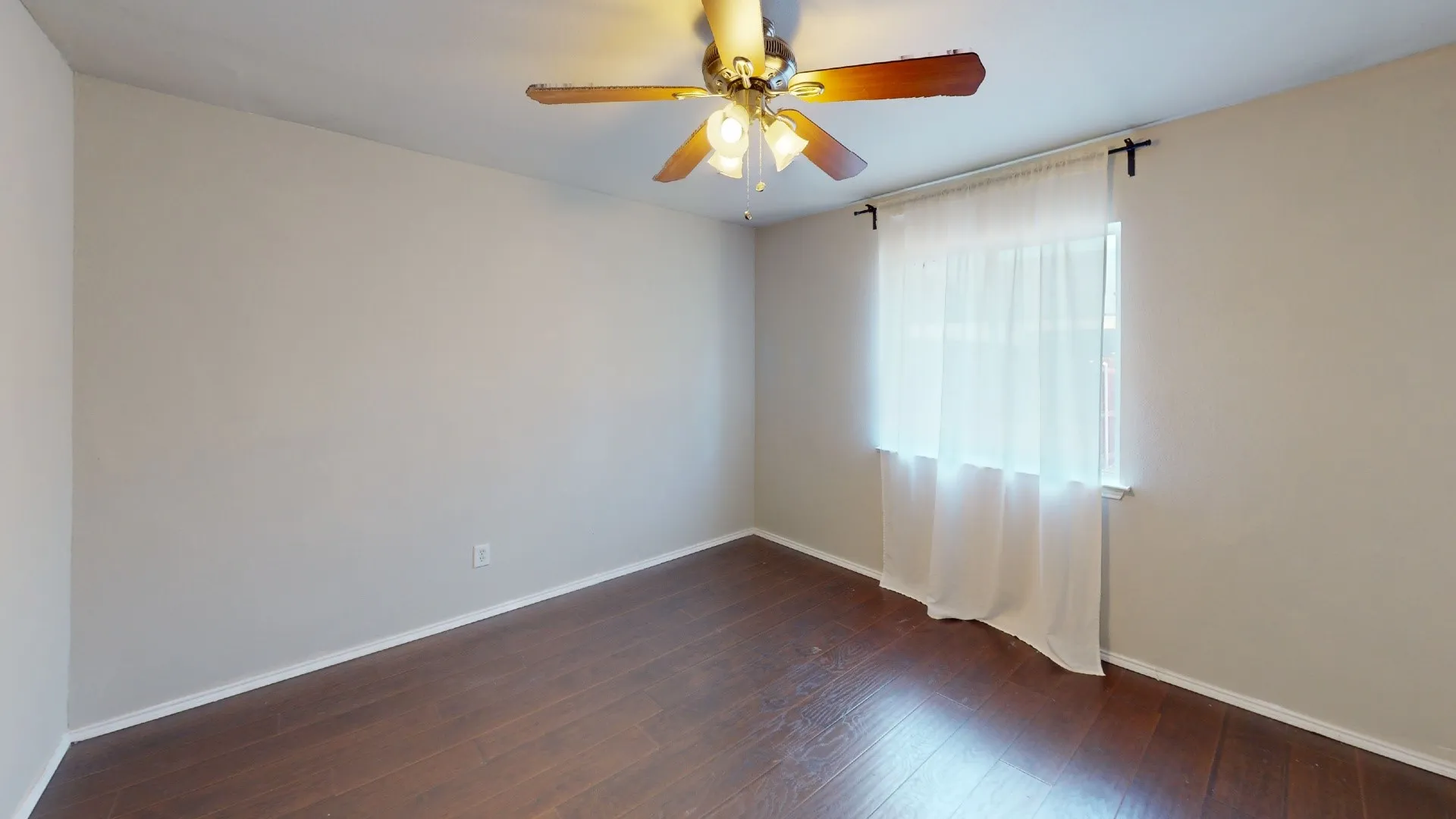 Room featuring wood-finish flooring, neutral wall paint, and a ceiling-mounted fan with integrated lighting